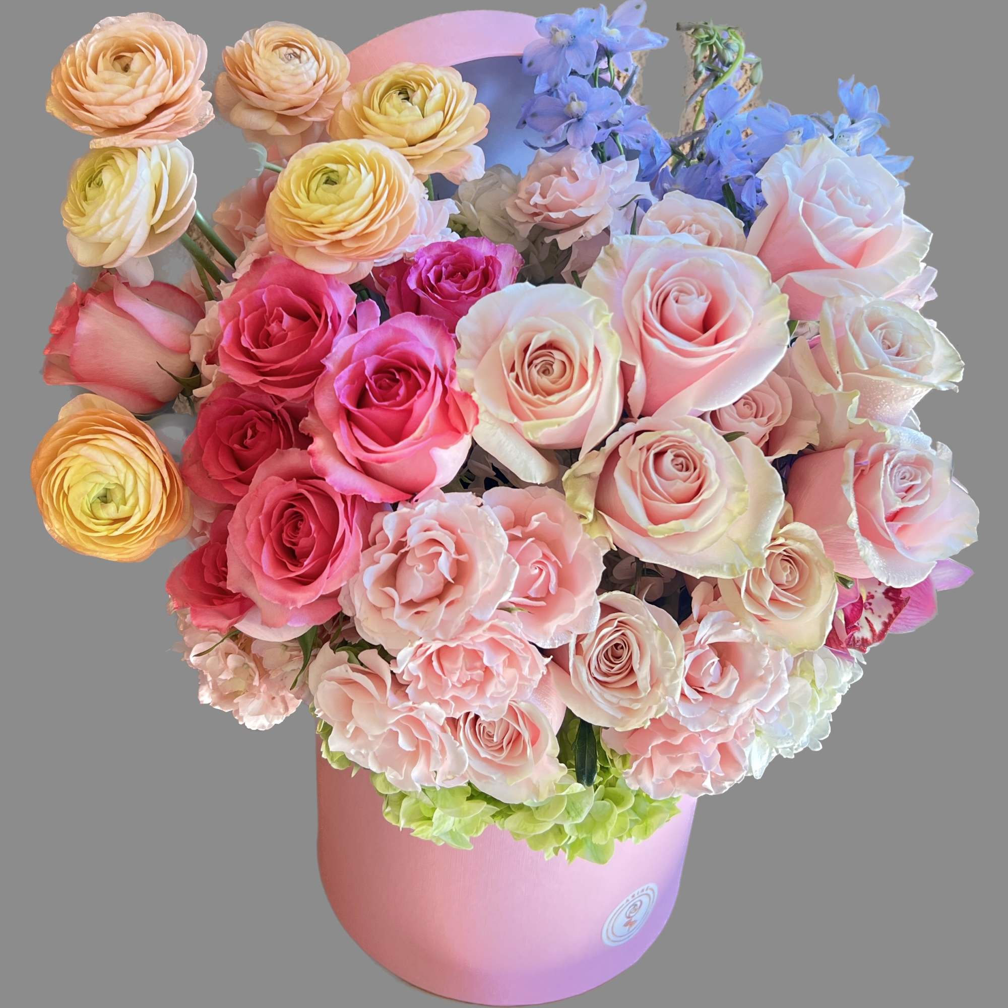 Mixed pastel roses and ranunculus in a pink hatbox