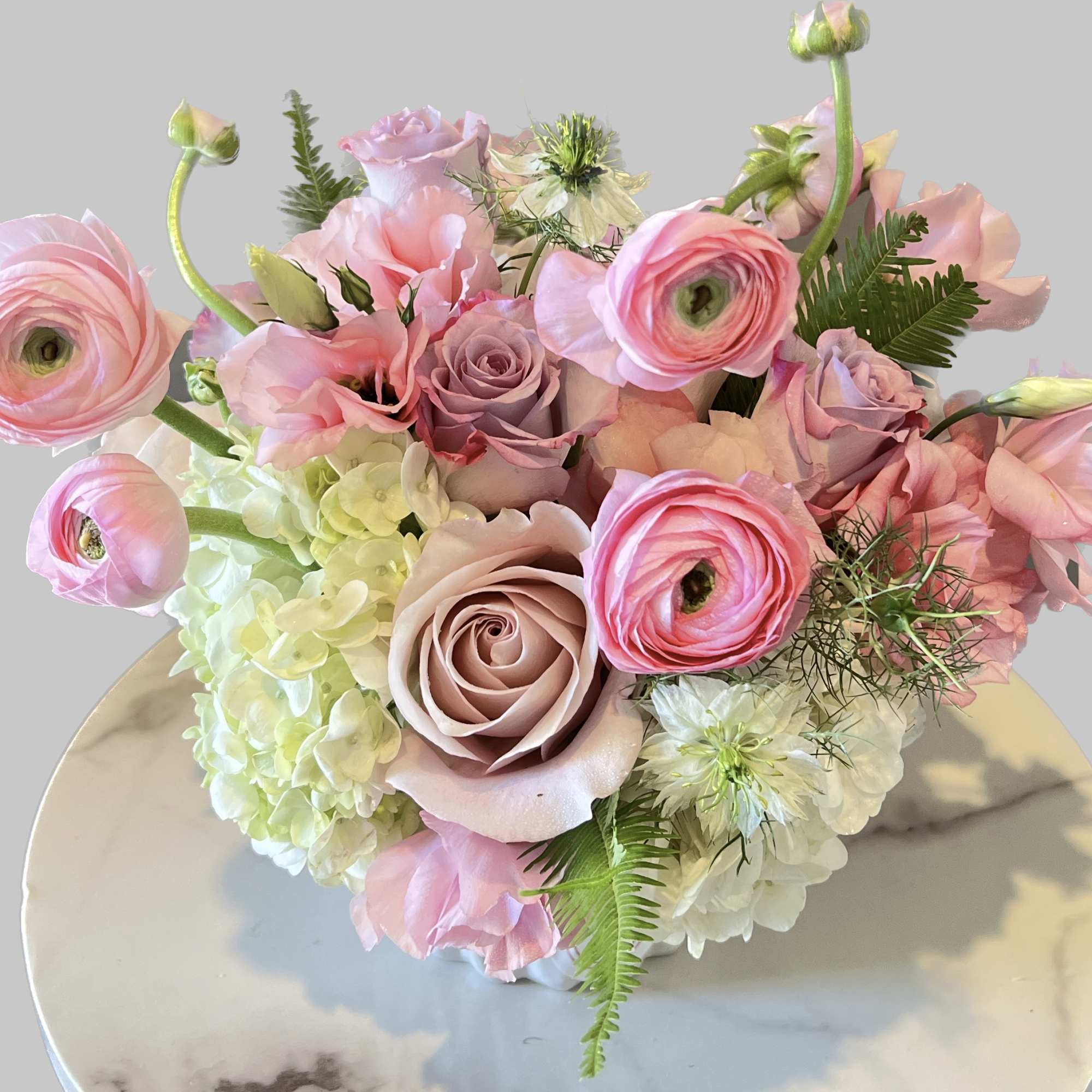 Pink and lavender bouquet with roses and ranunculus on a round table