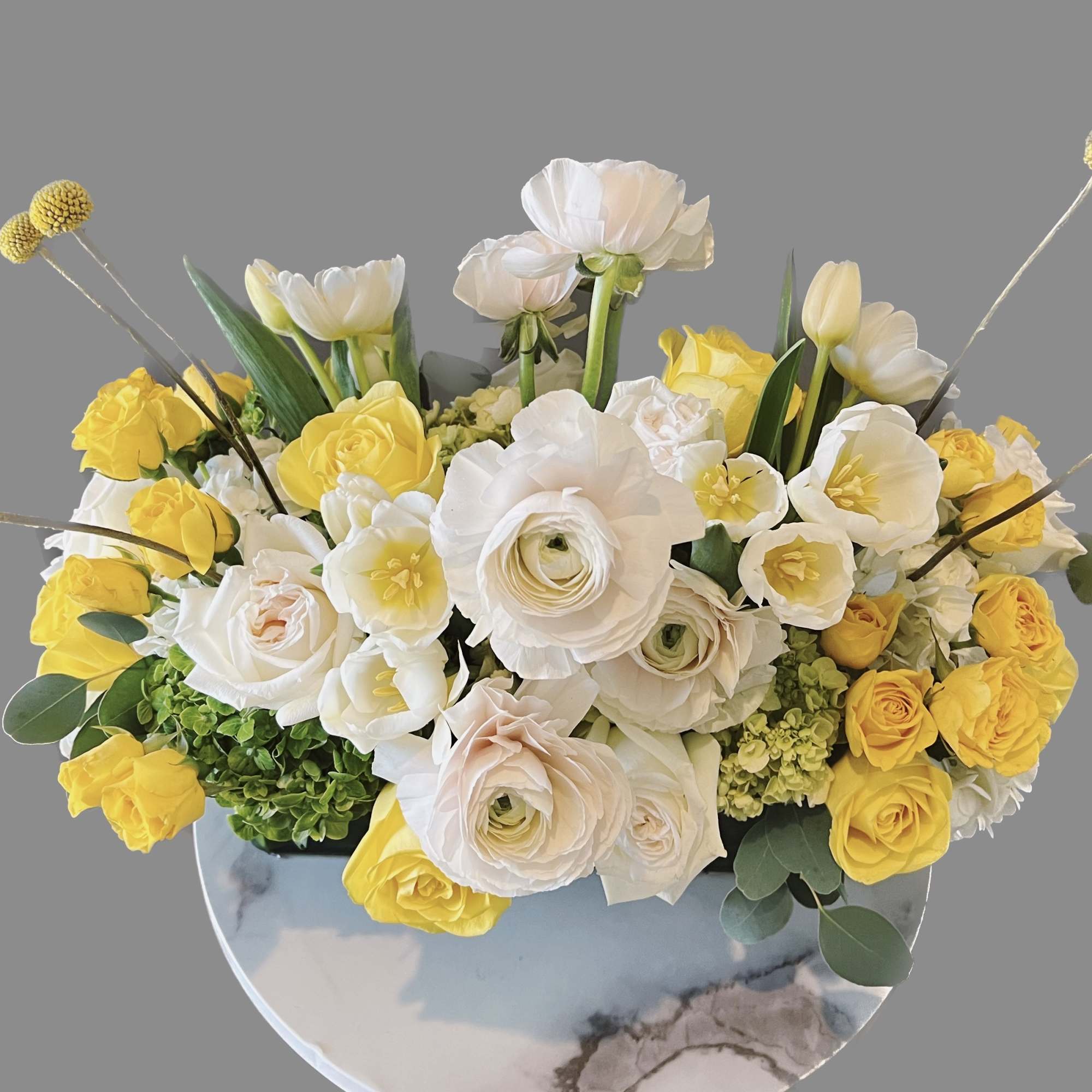 Yellow and white floral arrangement in a round vase