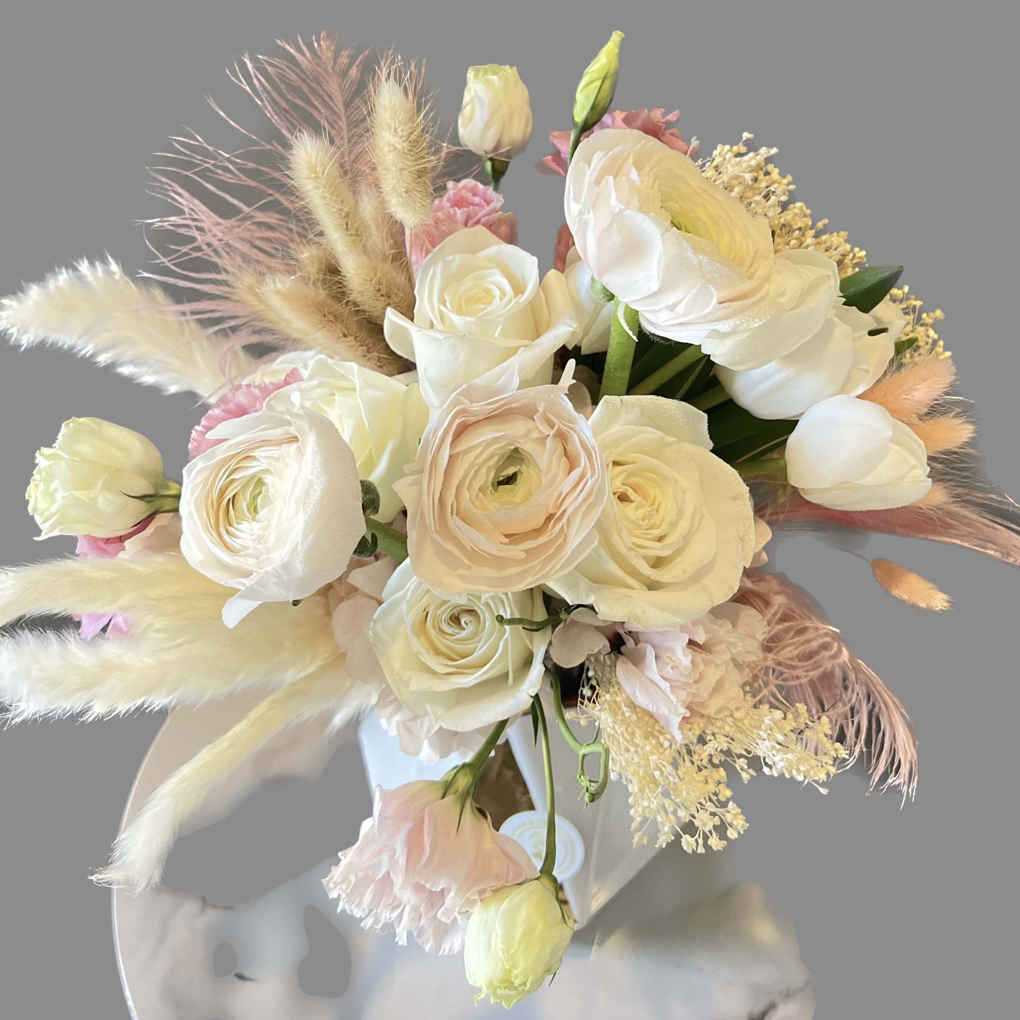 Cream and blush bouquet with roses and ranunculus in a white vase