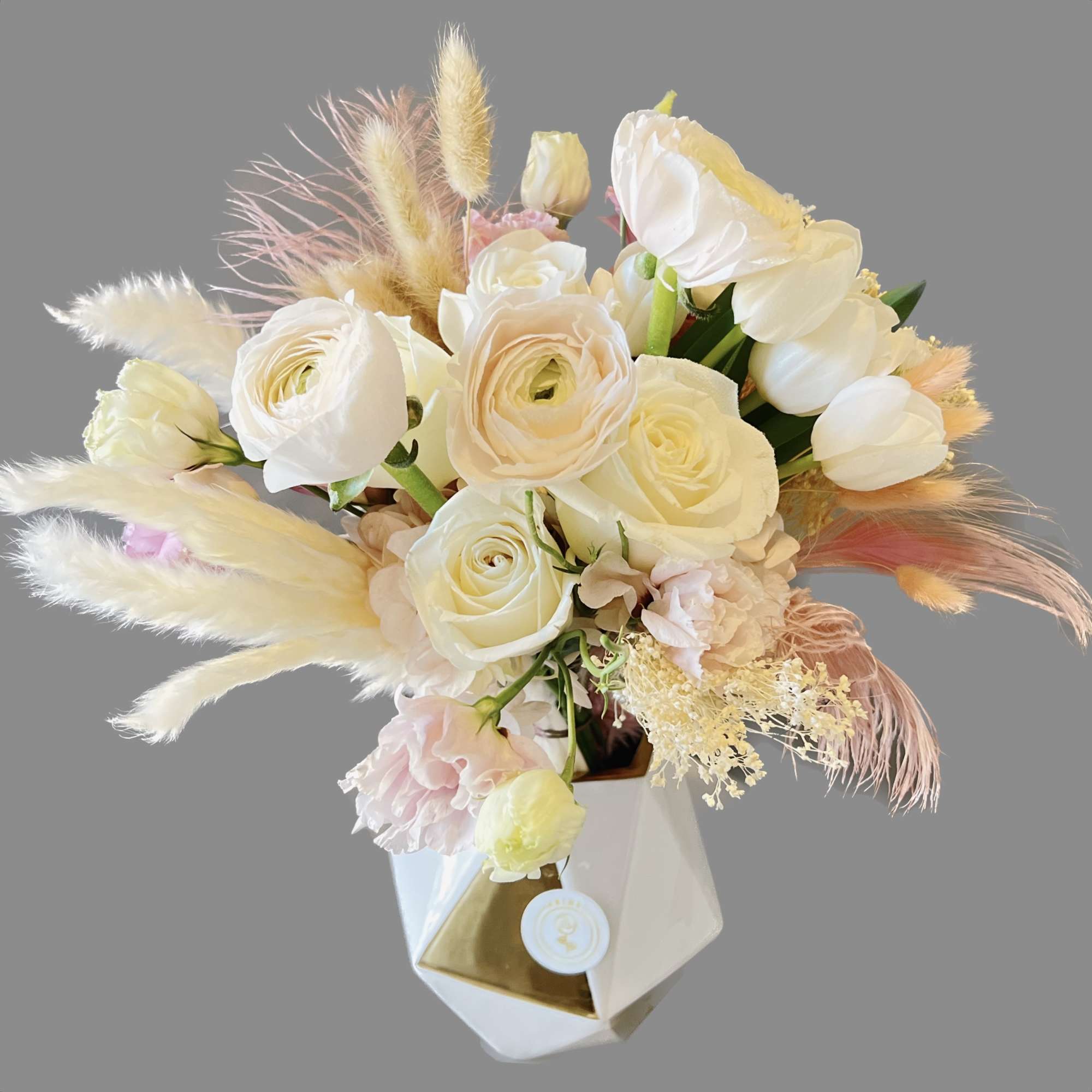 Cream rose bouquet with pastel dried grasses in a geometric vase