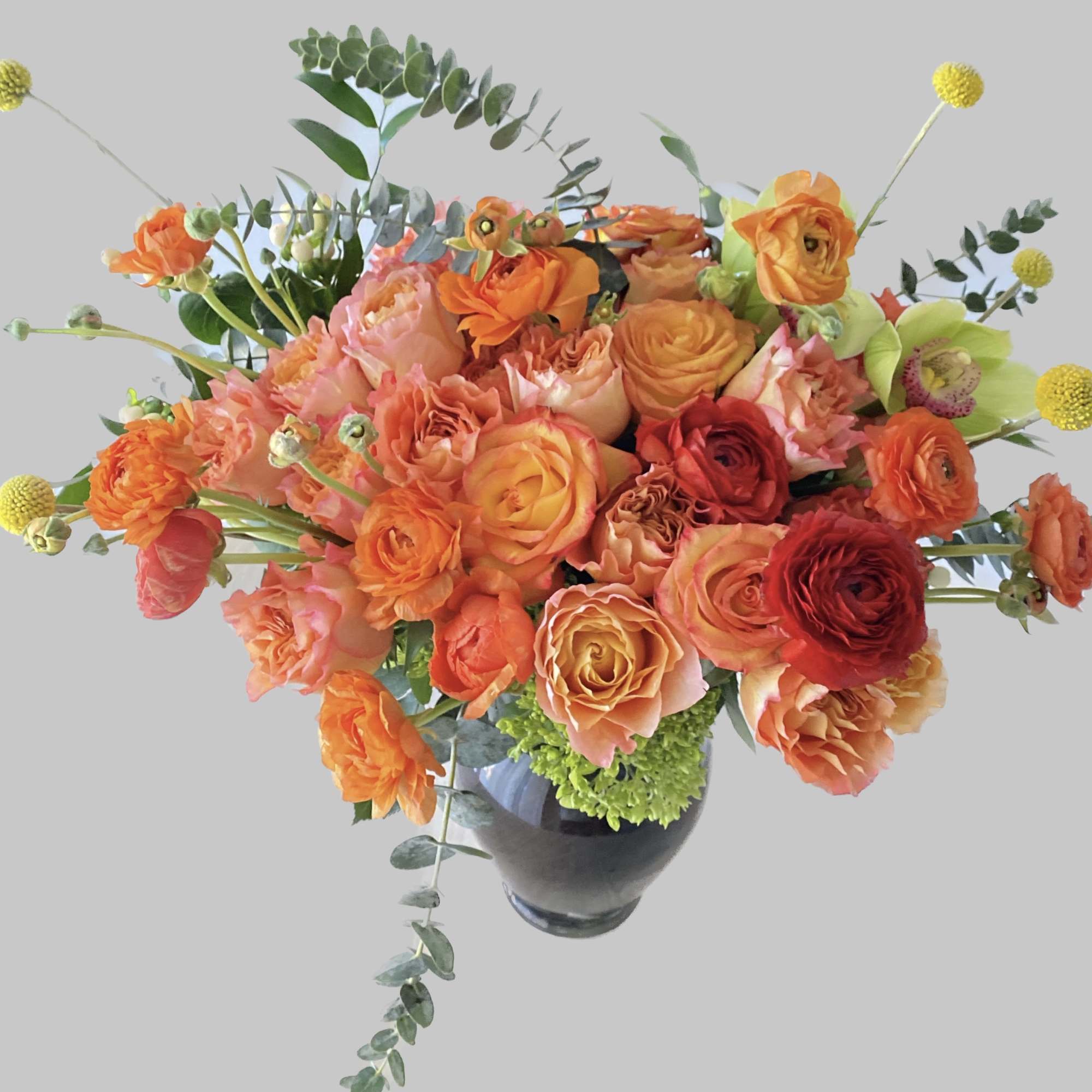 Orange and pink floral arrangement in a dark vase