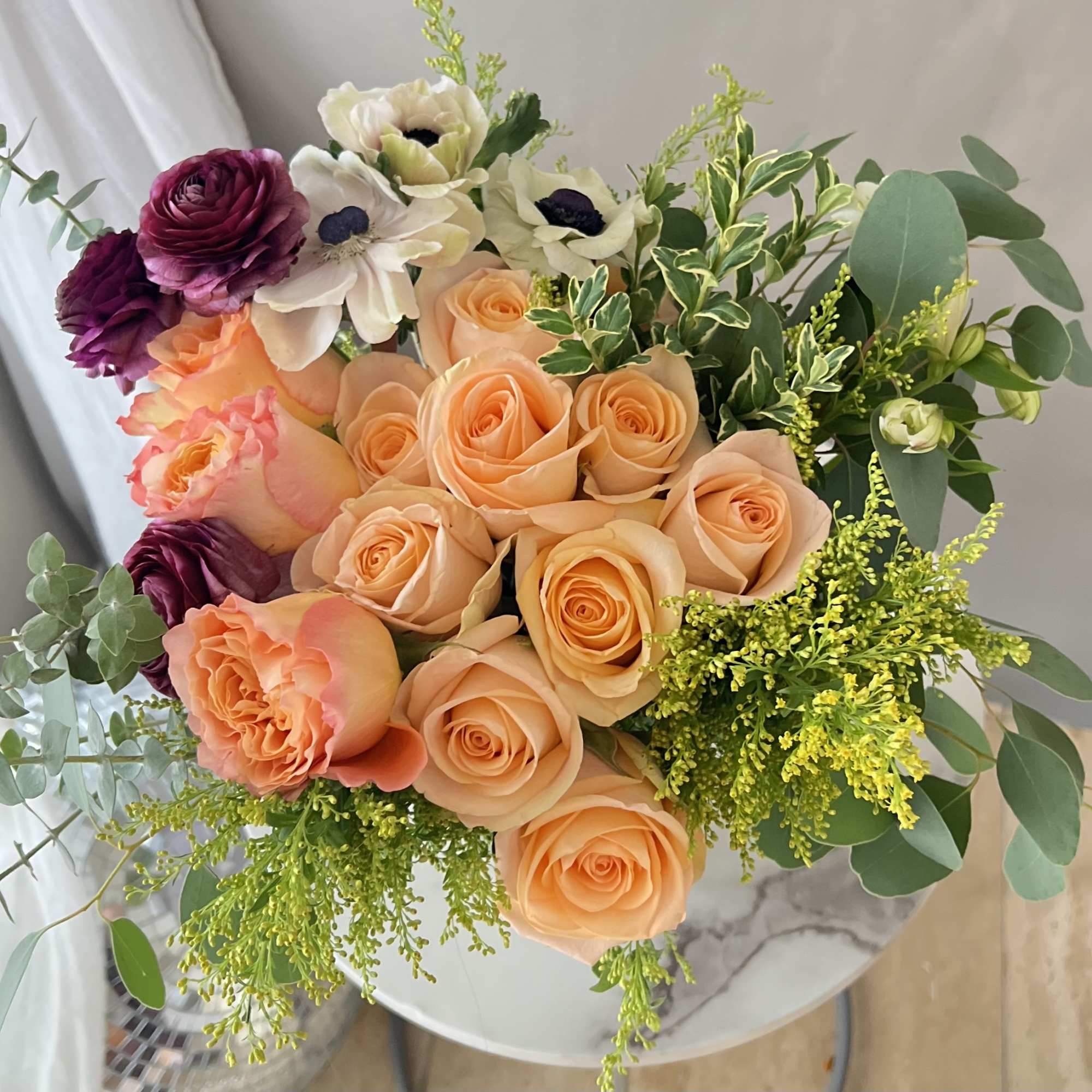 Bouquet of peach and purple roses with white flowers and greenery