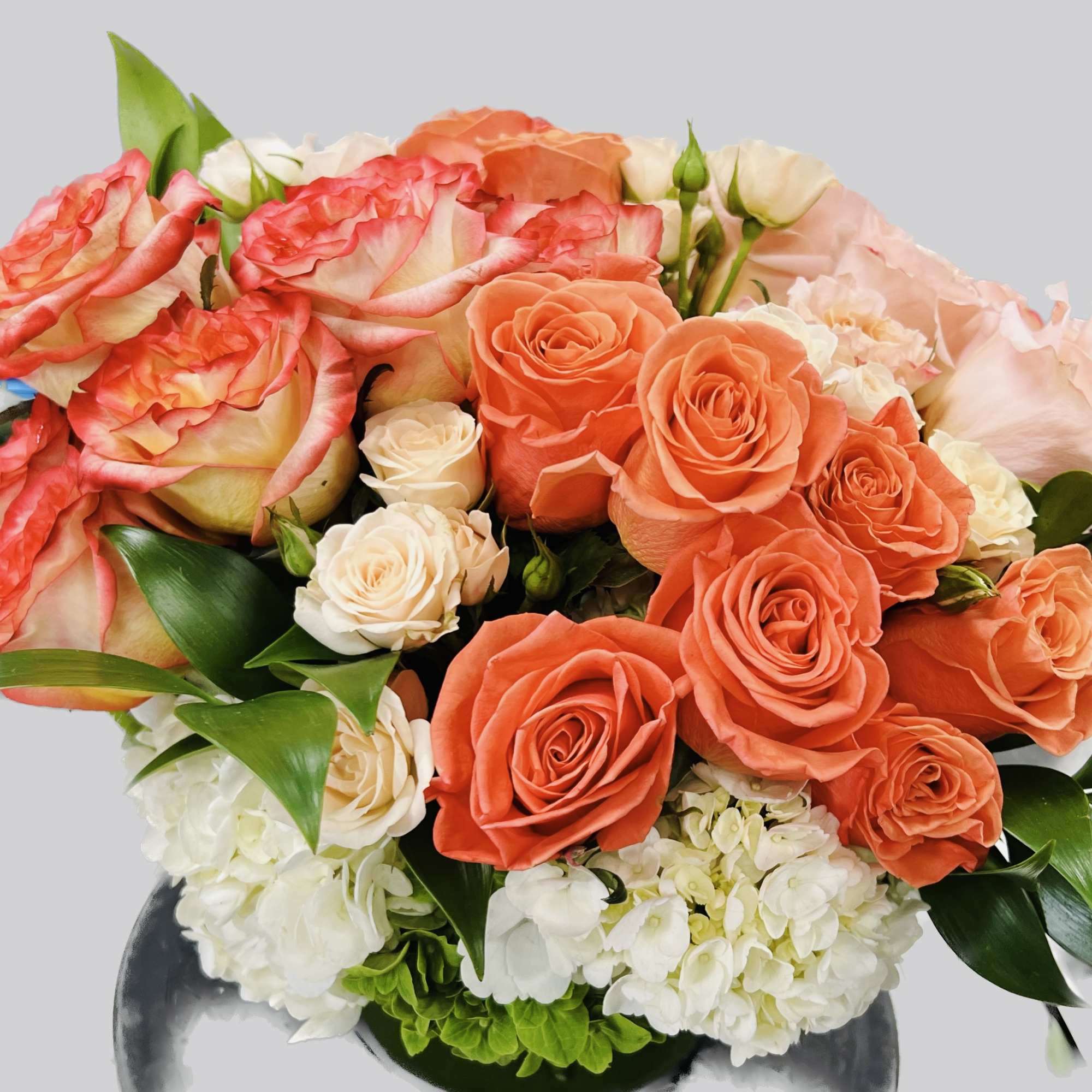 Bouquet of orange and pink roses with white hydrangeas in a vase