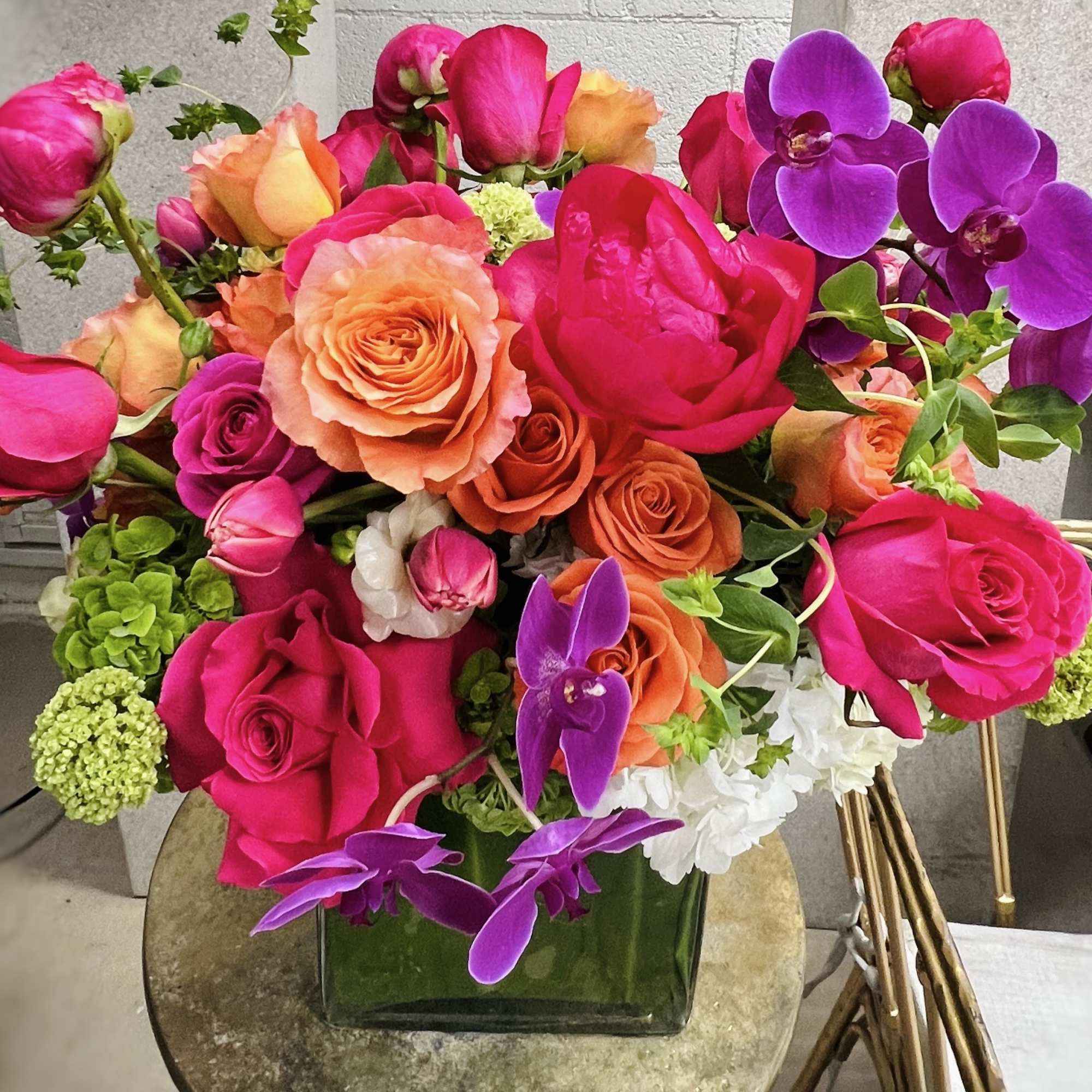 Bright bouquet of pink, orange, and purple roses in a square glass vase