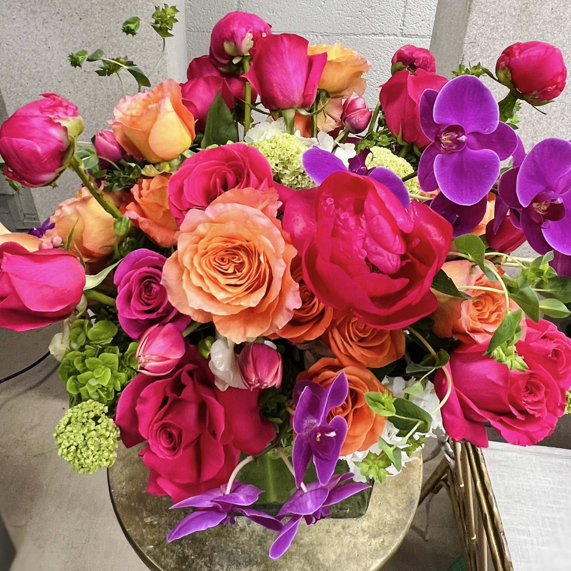Bouquet of pink and orange roses with purple orchids in a vase