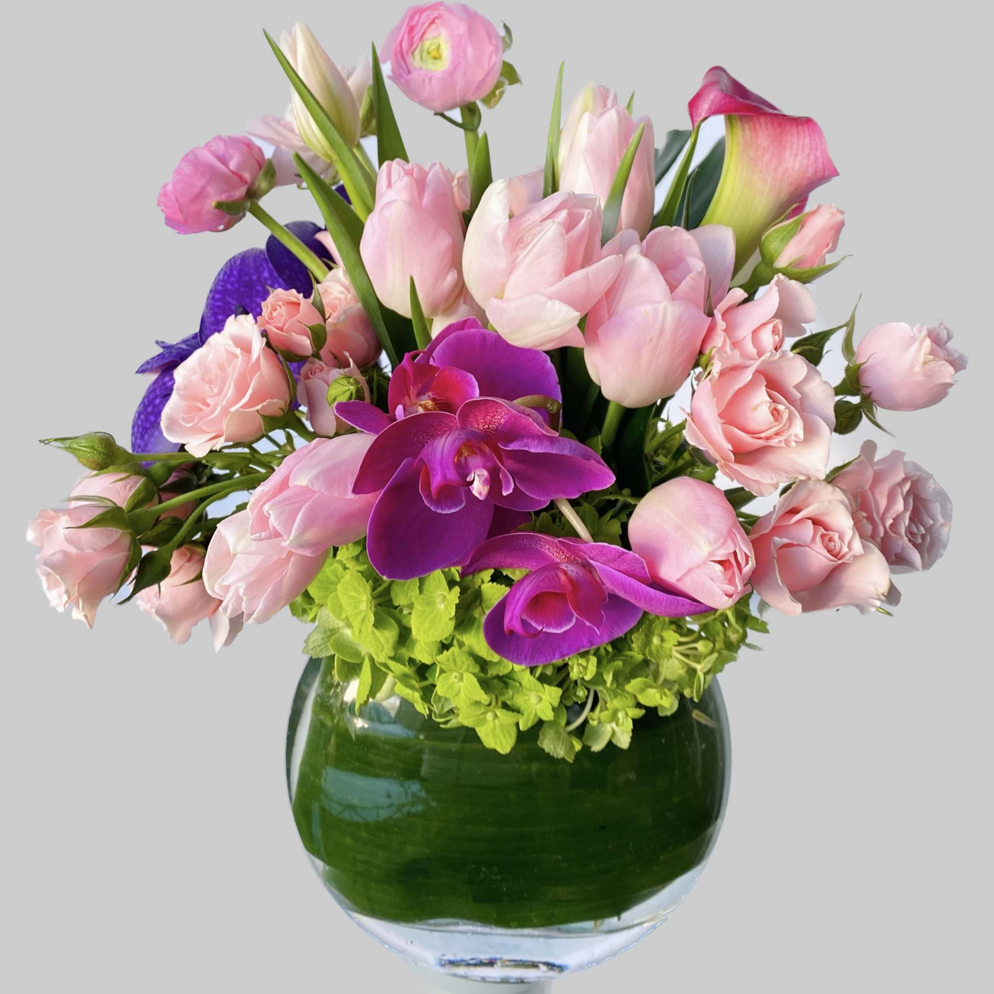 Pink tulips, roses, and purple orchids in a glass vase