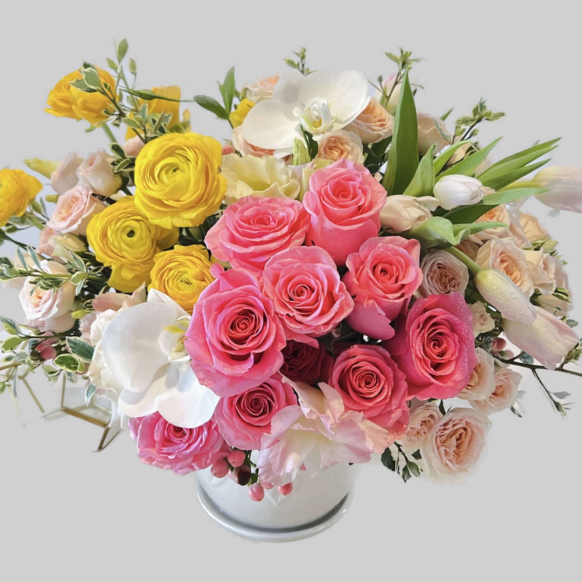 Bouquet of pink and yellow roses with white orchids in a vase