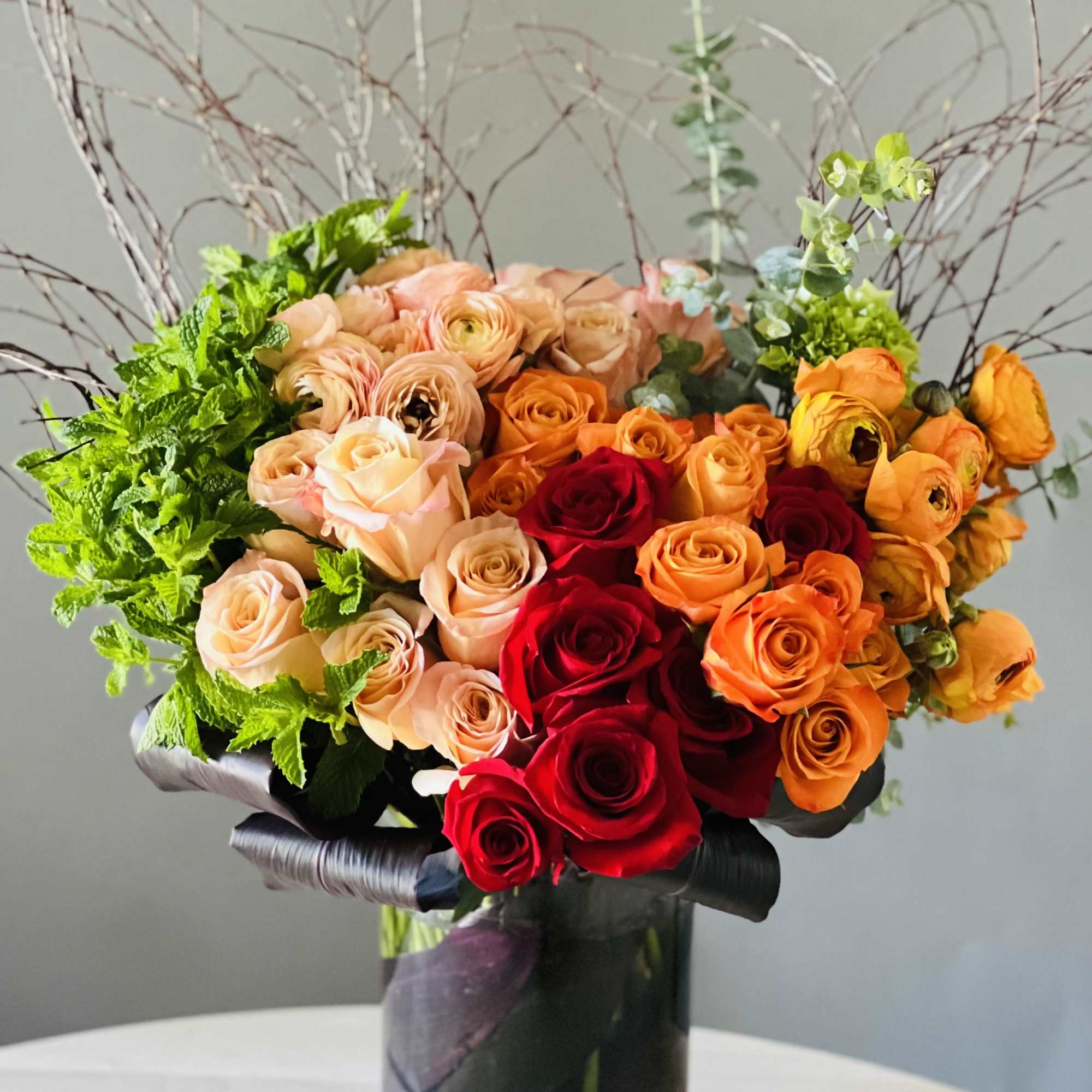 Mixed roses in a black vase with curly branches