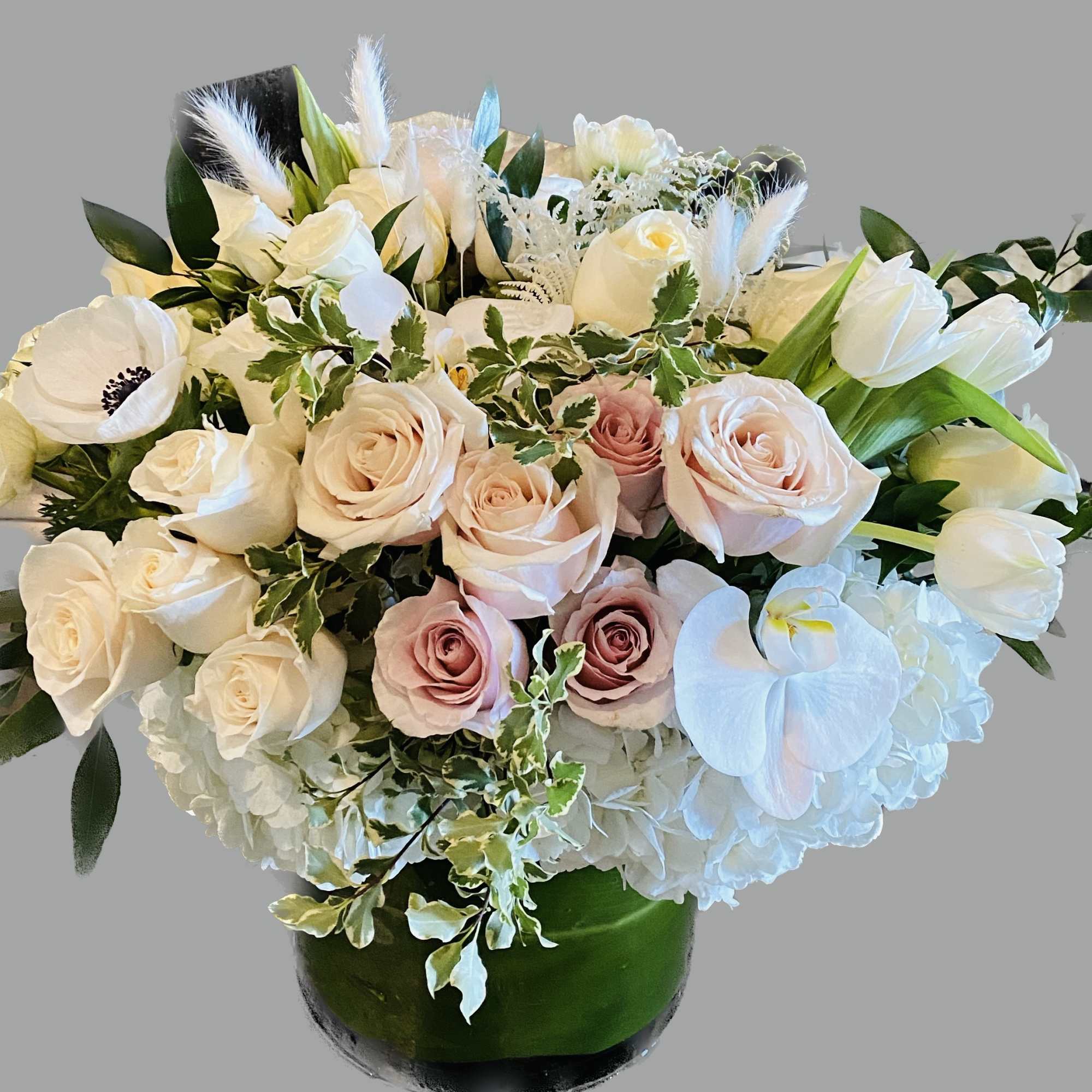 Bouquet of white and blush roses with white orchids in a green vase