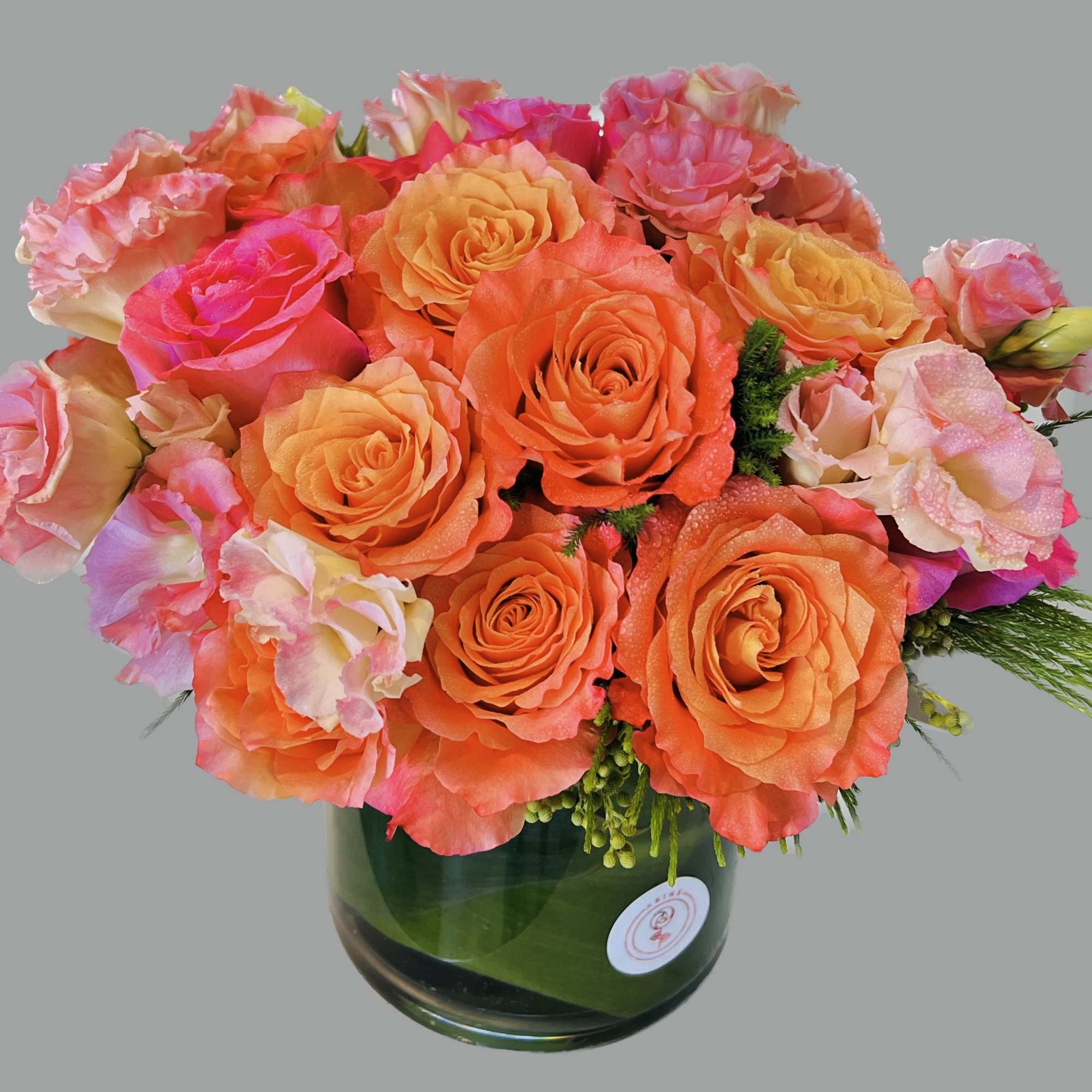 Bouquet of orange and pink roses in a green glass vase