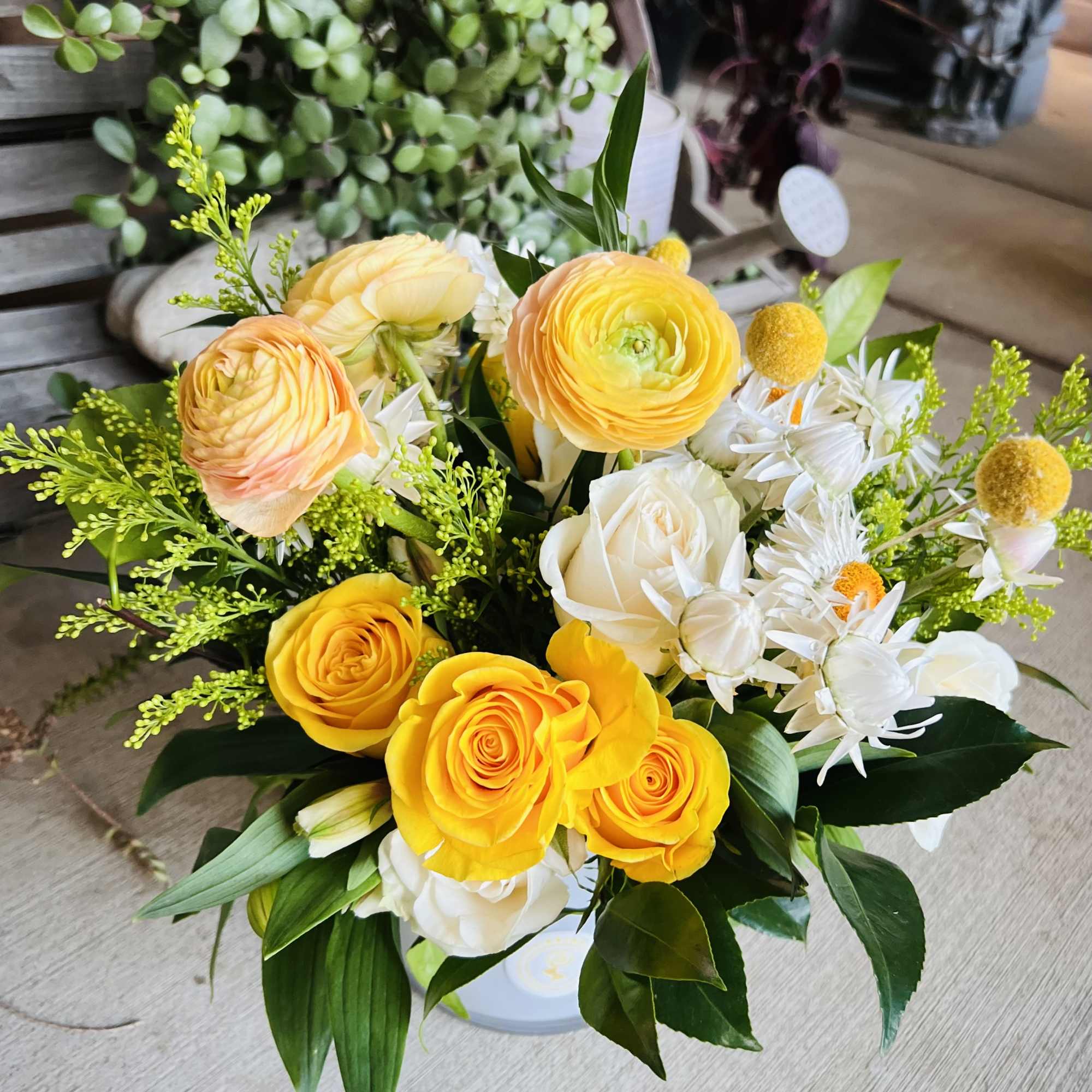 Bouquet of yellow and white roses with white daisy-like flowers in a vase