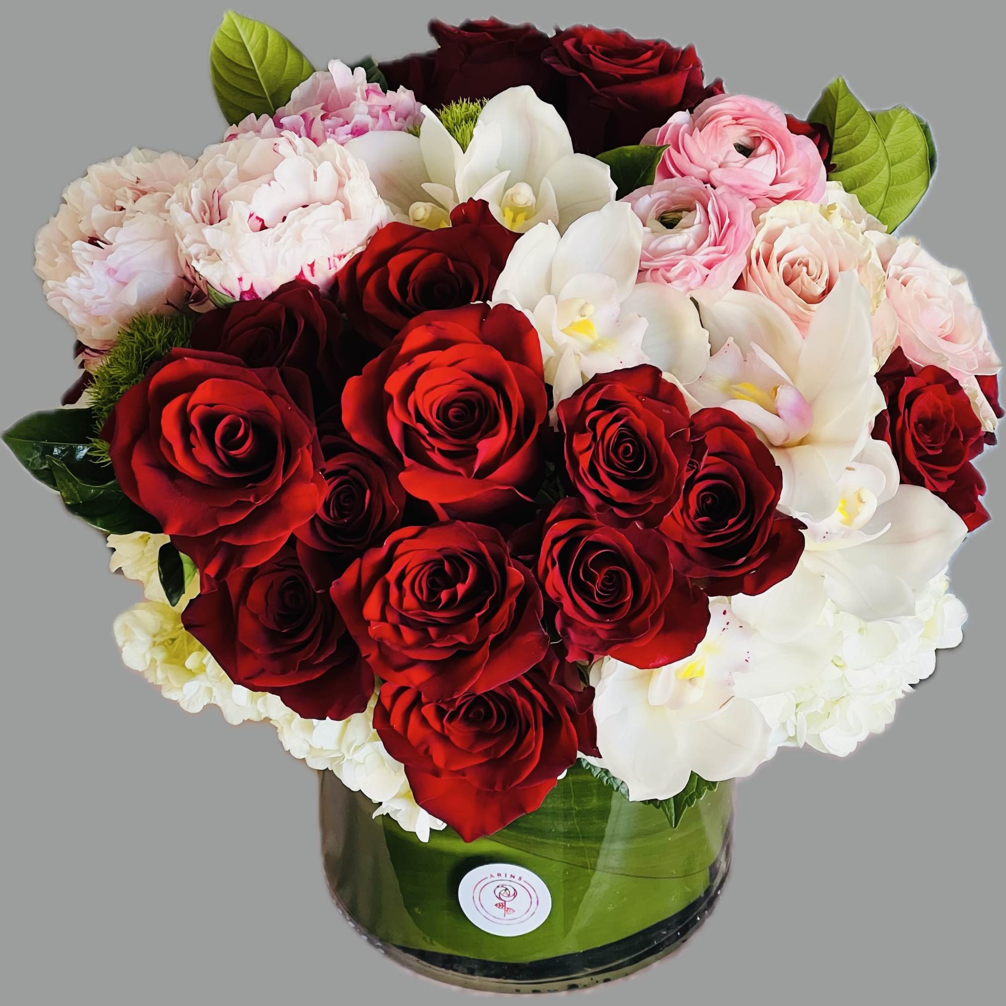 Red roses and white orchids arranged in a round glass vase