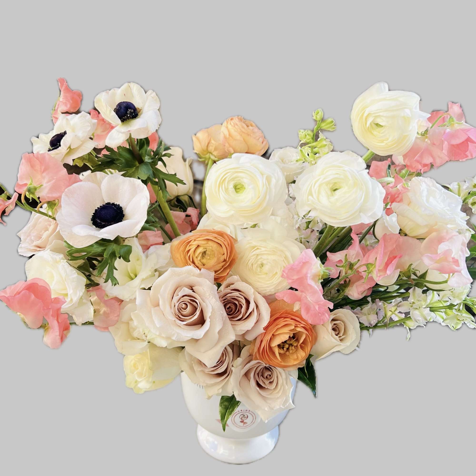 Bouquet of cream, peach, and pink flowers in a white vase
