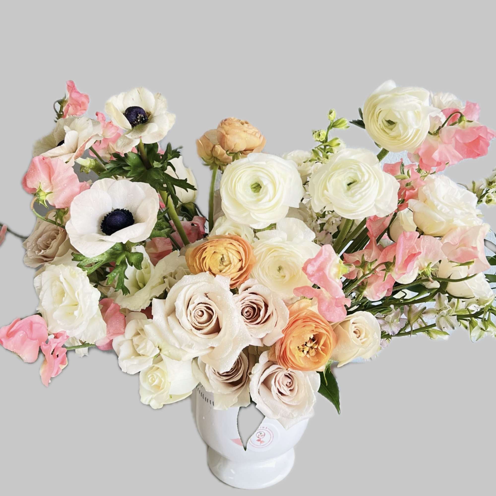 Bouquet of white, blush, and peach flowers in a white vase