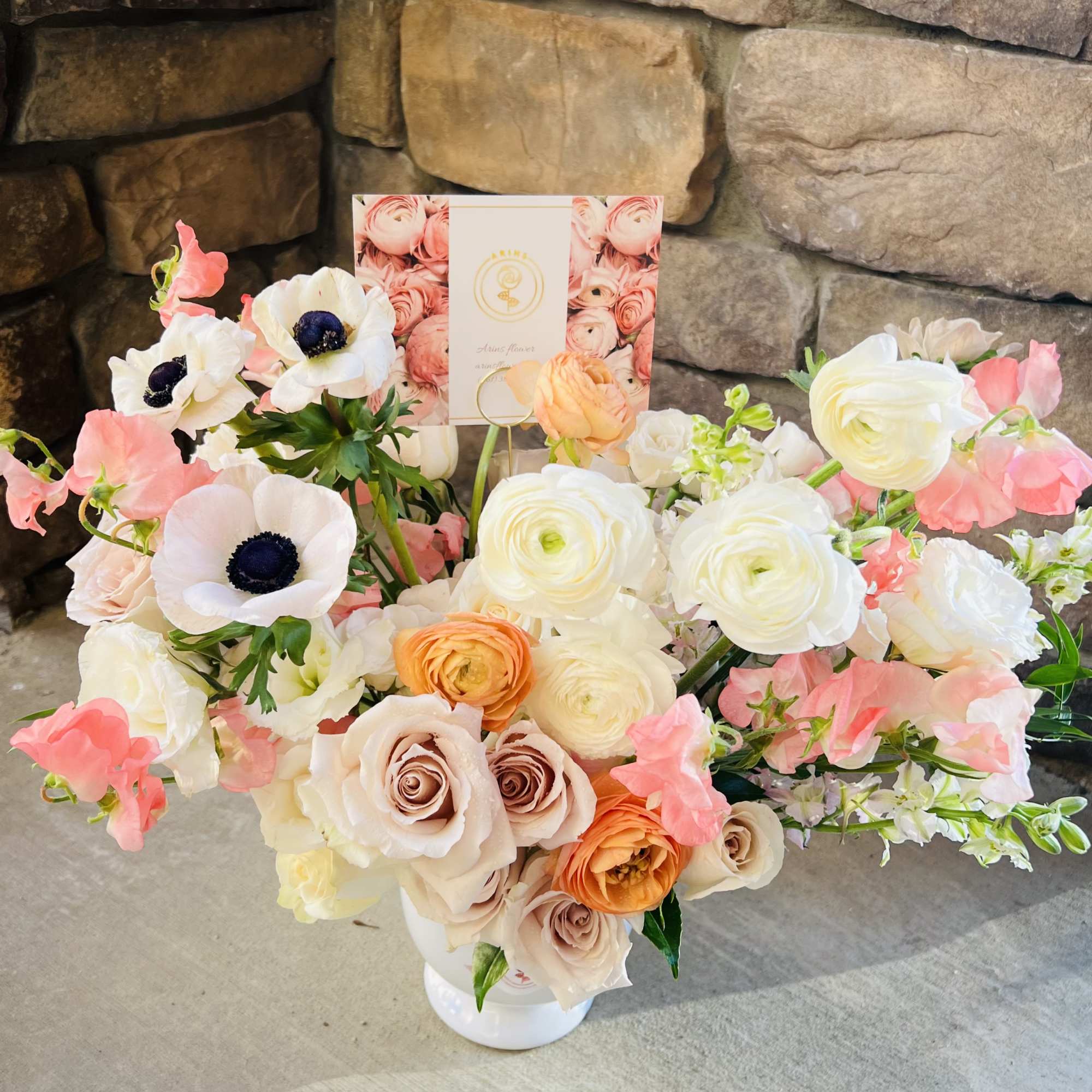 Pastel bouquet with white anemones, roses, and ranunculus in a white vase