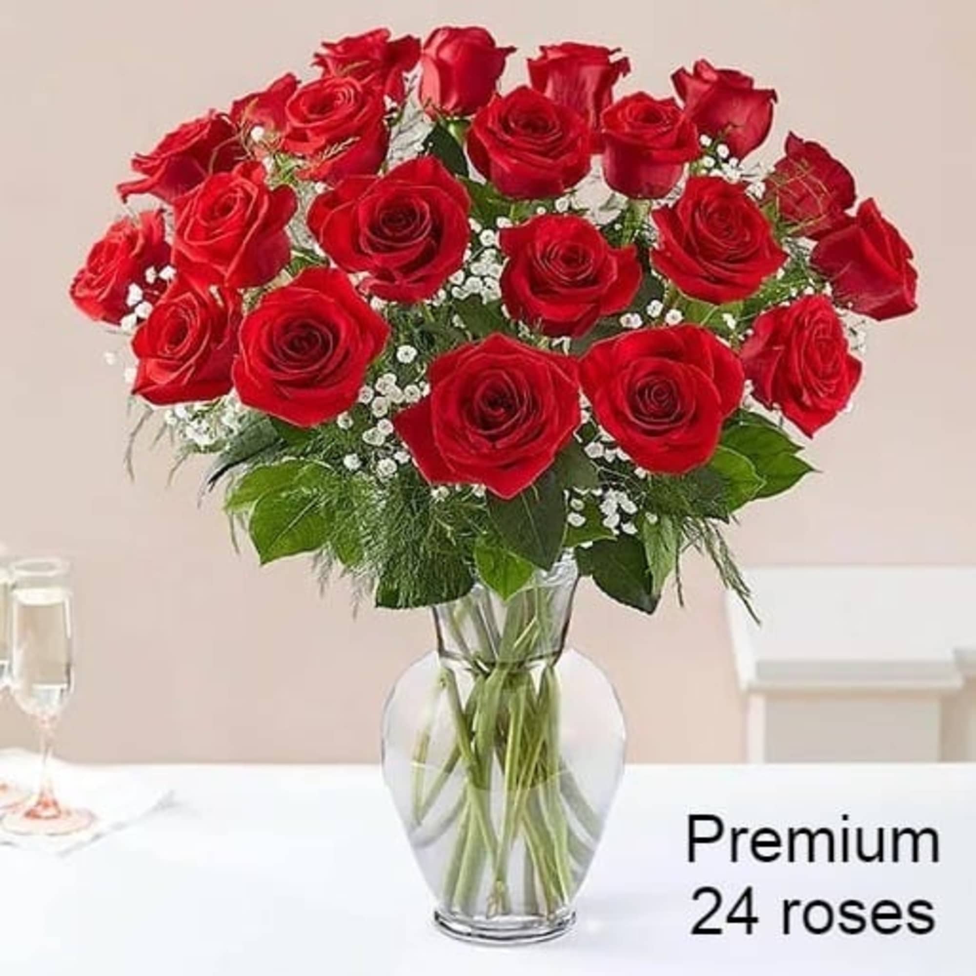 Arrangement of 24 red roses with white filler flowers in a clear glass vase