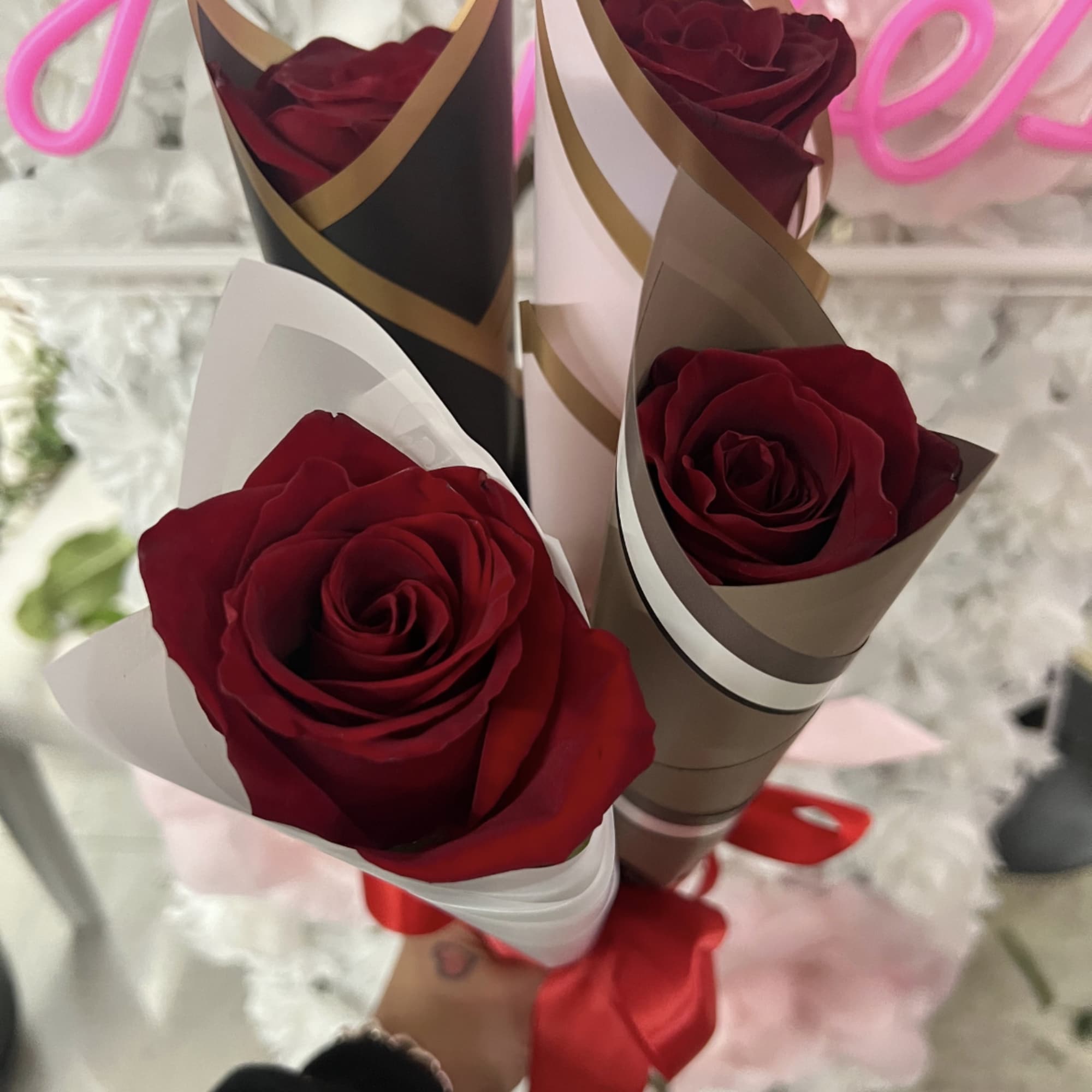Three red roses wrapped in decorative paper with a red ribbon