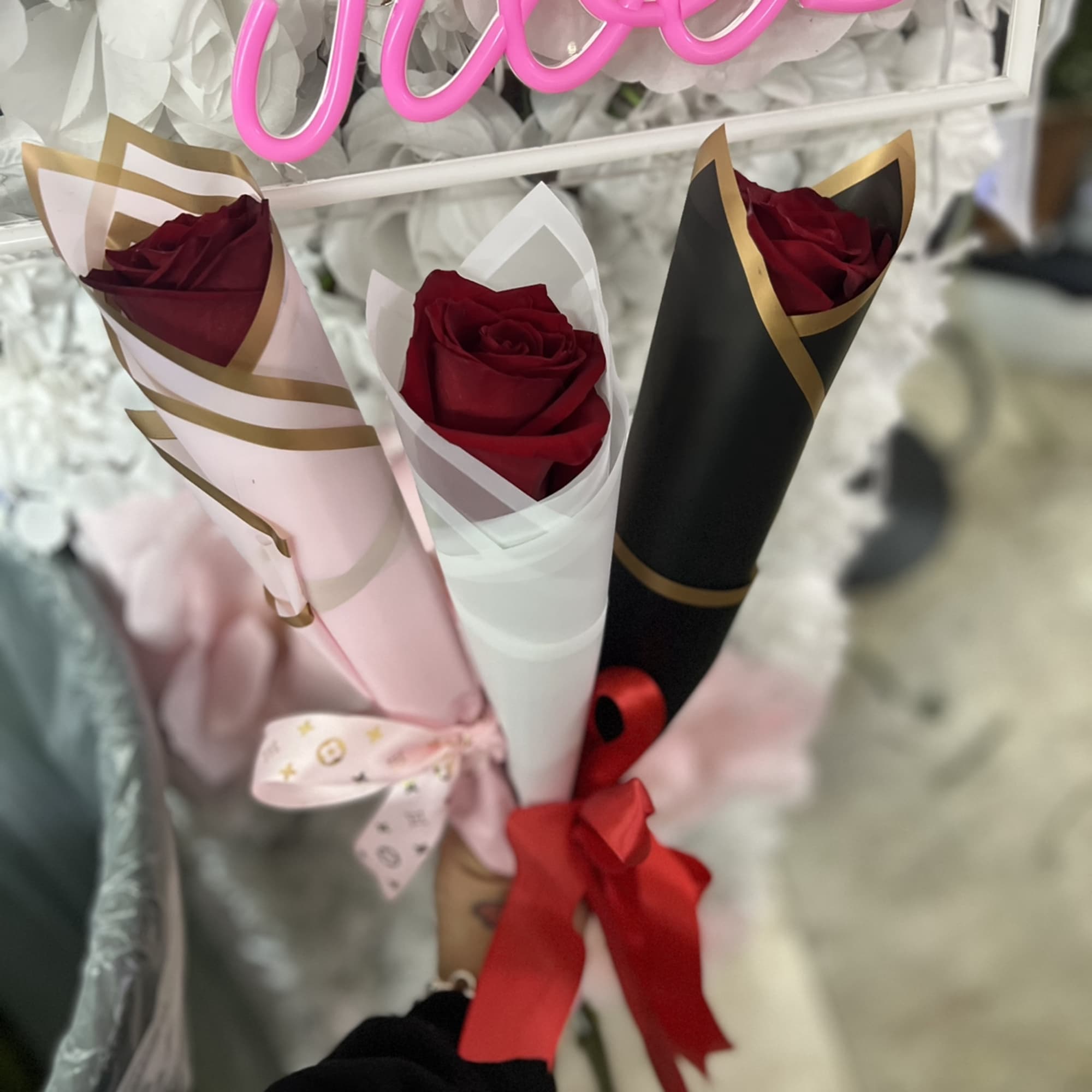 Three single red roses wrapped in pink, white, and black paper