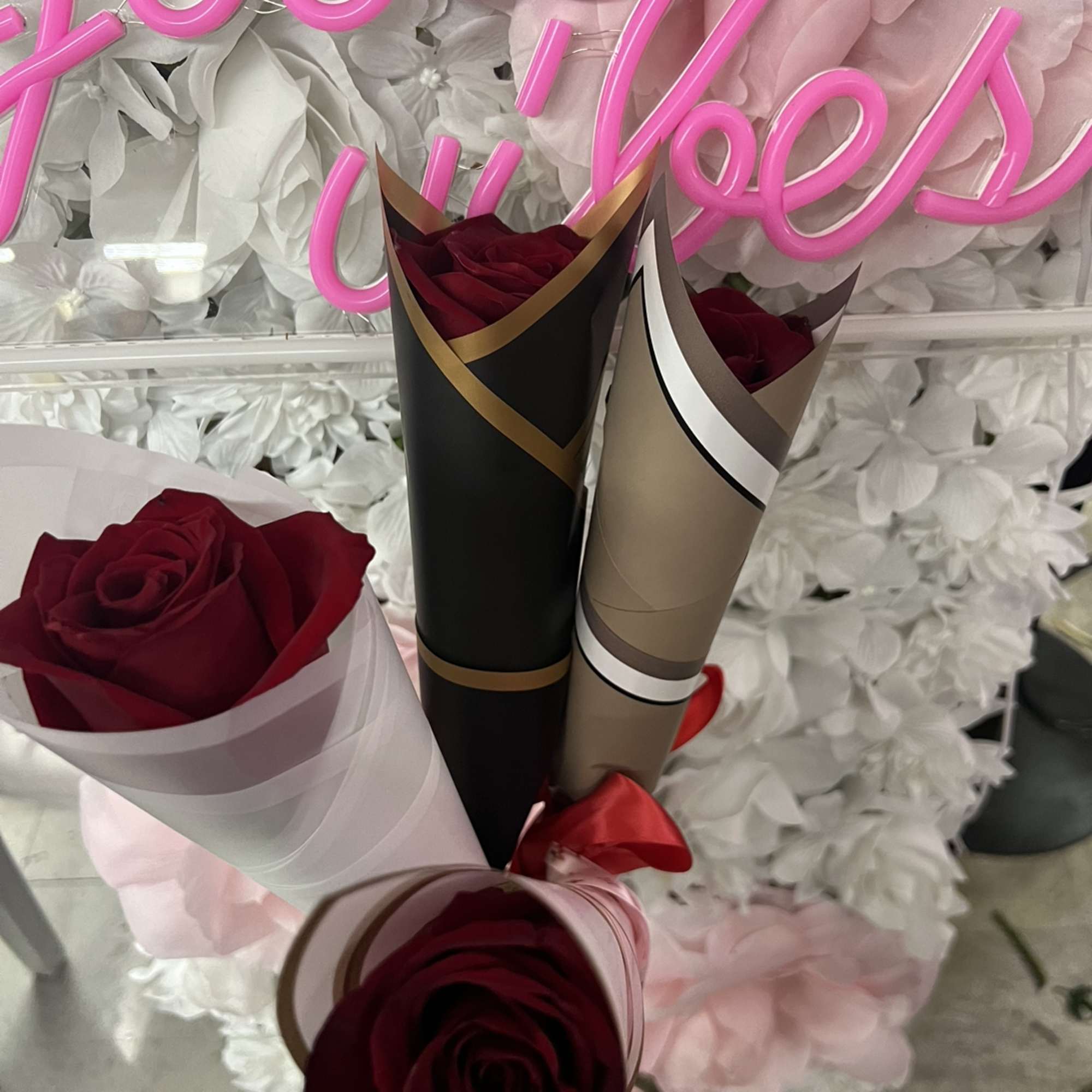 Red roses wrapped in decorative paper with a pink floral backdrop