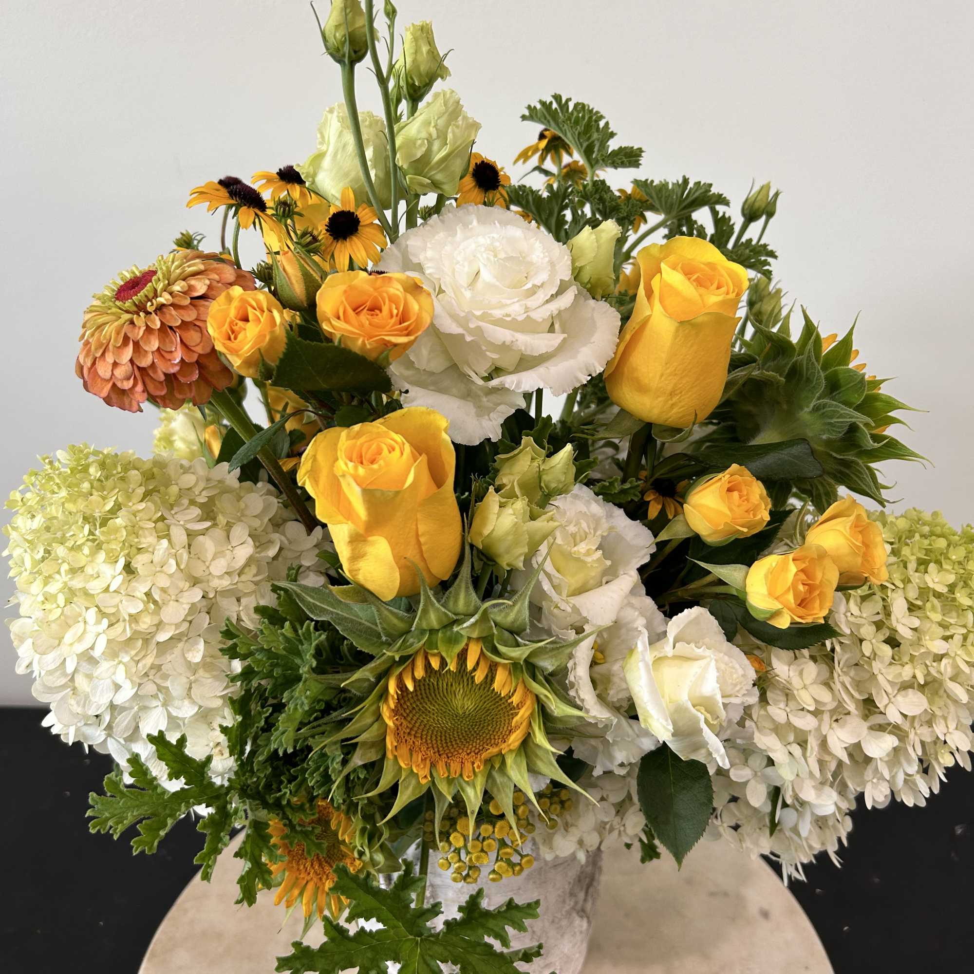 Mixed bouquet with yellow roses, white blooms, sunflowers, and hydrangeas in a vase