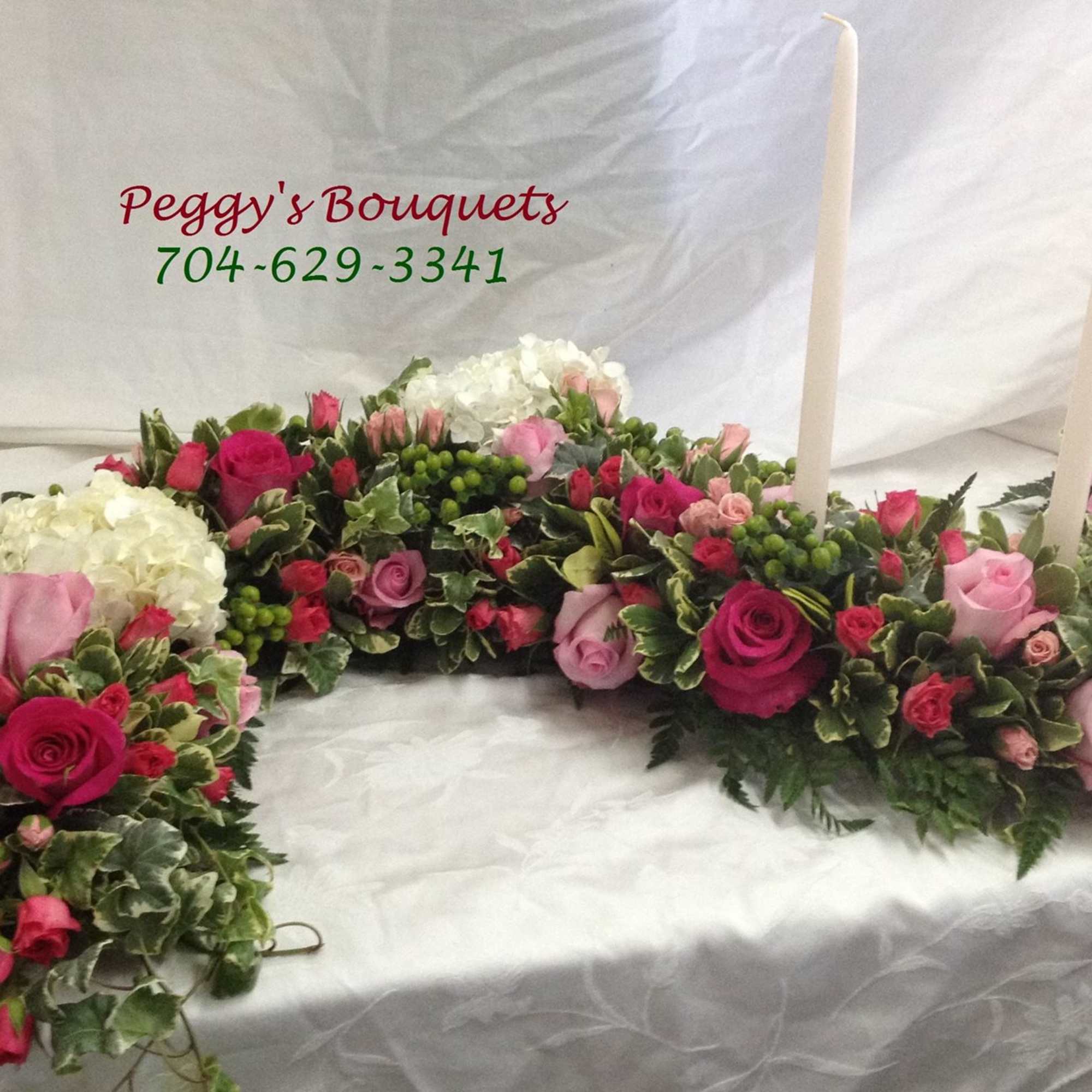 Pink and white floral casket spray with tall taper candles