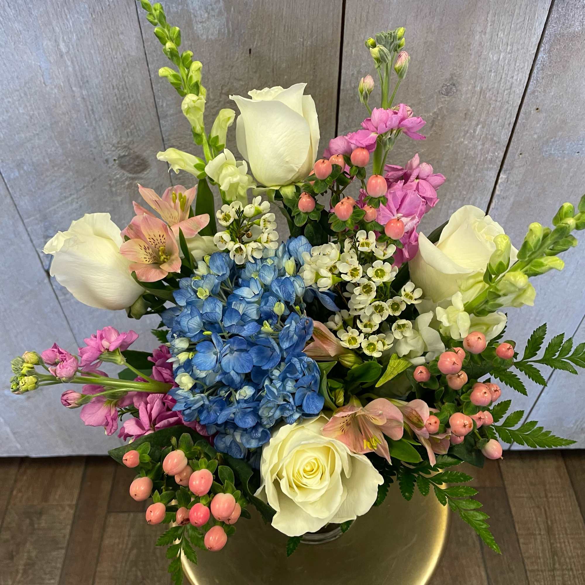 Bouquet of white roses, blue hydrangea, and pink flowers in a vase