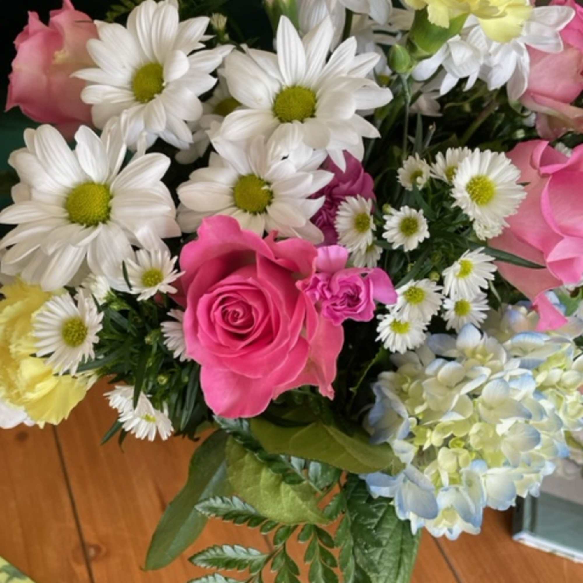 Bouquet of pink roses, white daisies, and pale hydrangea blooms