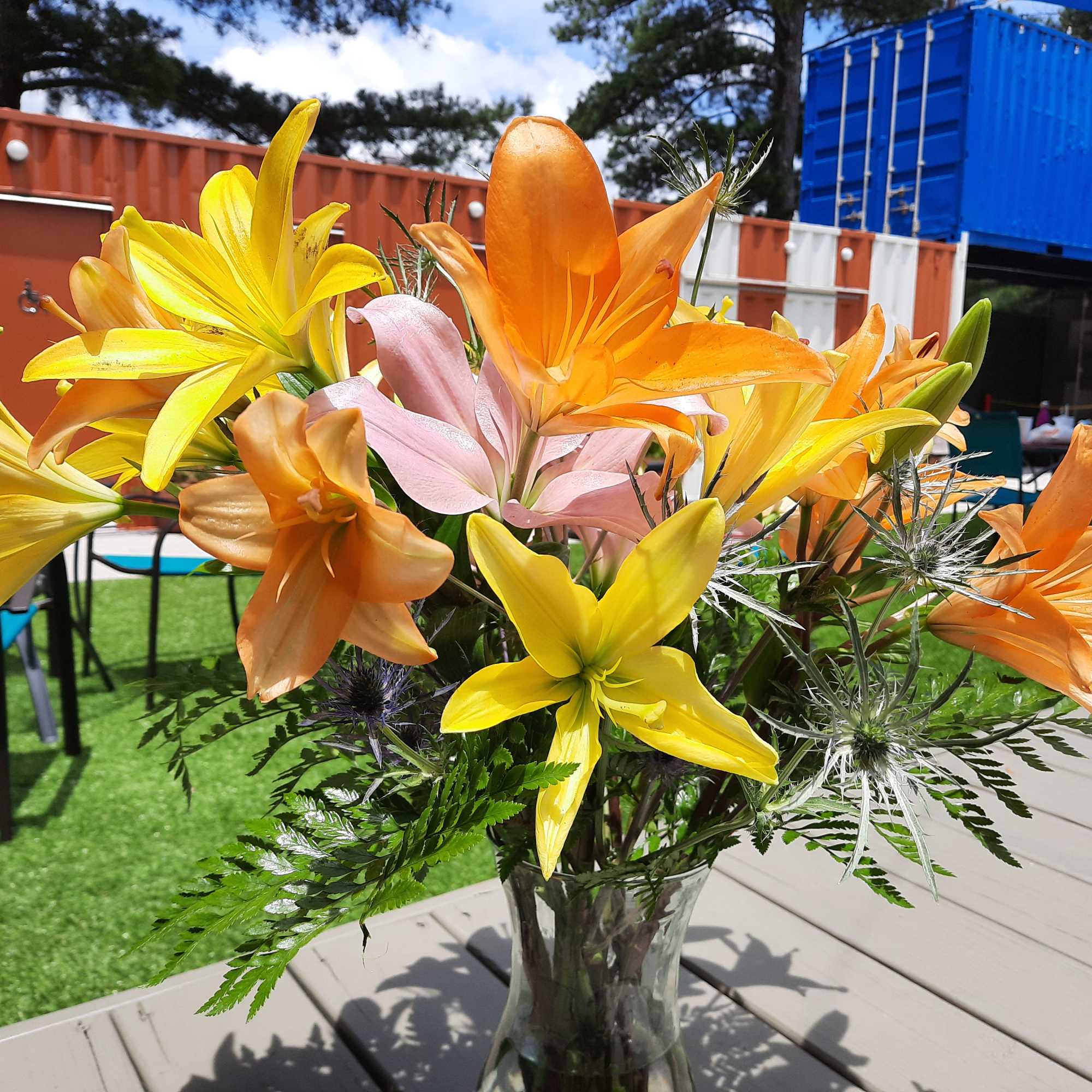 Bouquet of yellow, orange, and pink lilies in a glass vase