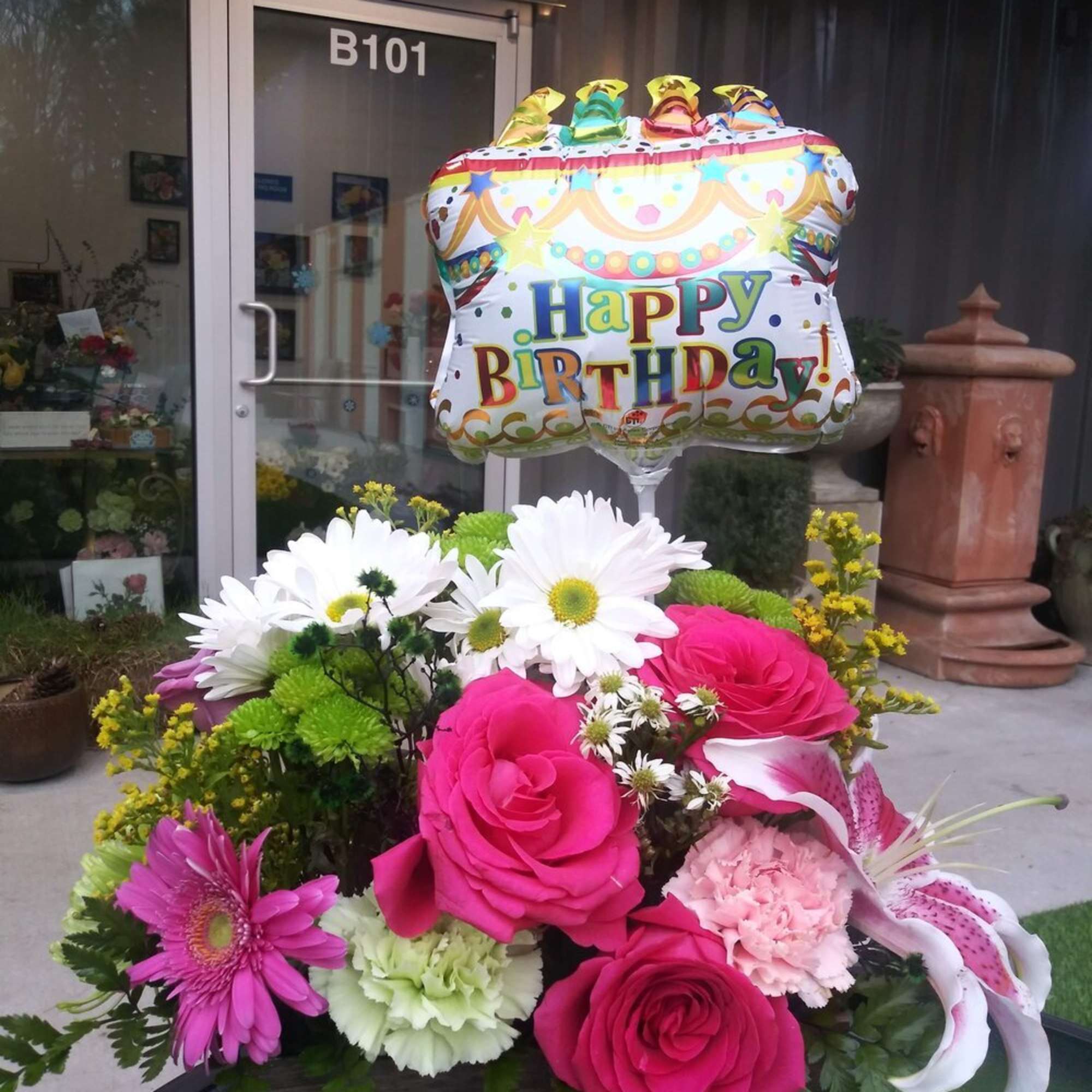 Birthday balloon above a colorful flower arrangement in a basket