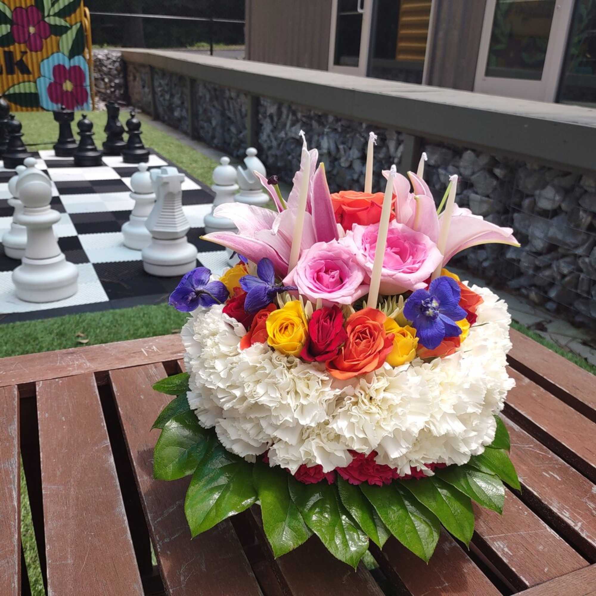 Round floral arrangement with pink lilies, roses, and white hydrangeas