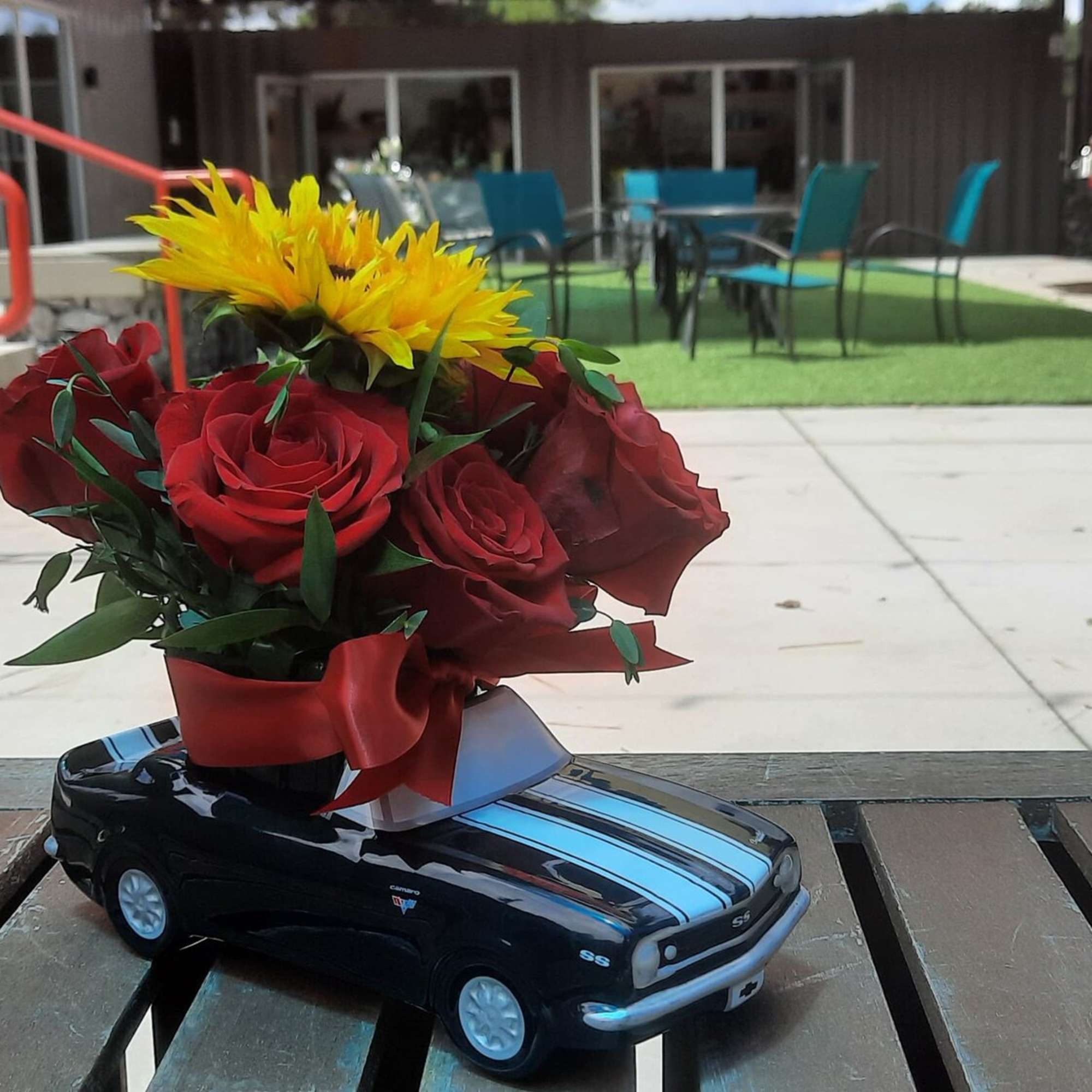 Bouquet of red roses and a yellow sunflower in a toy car vase