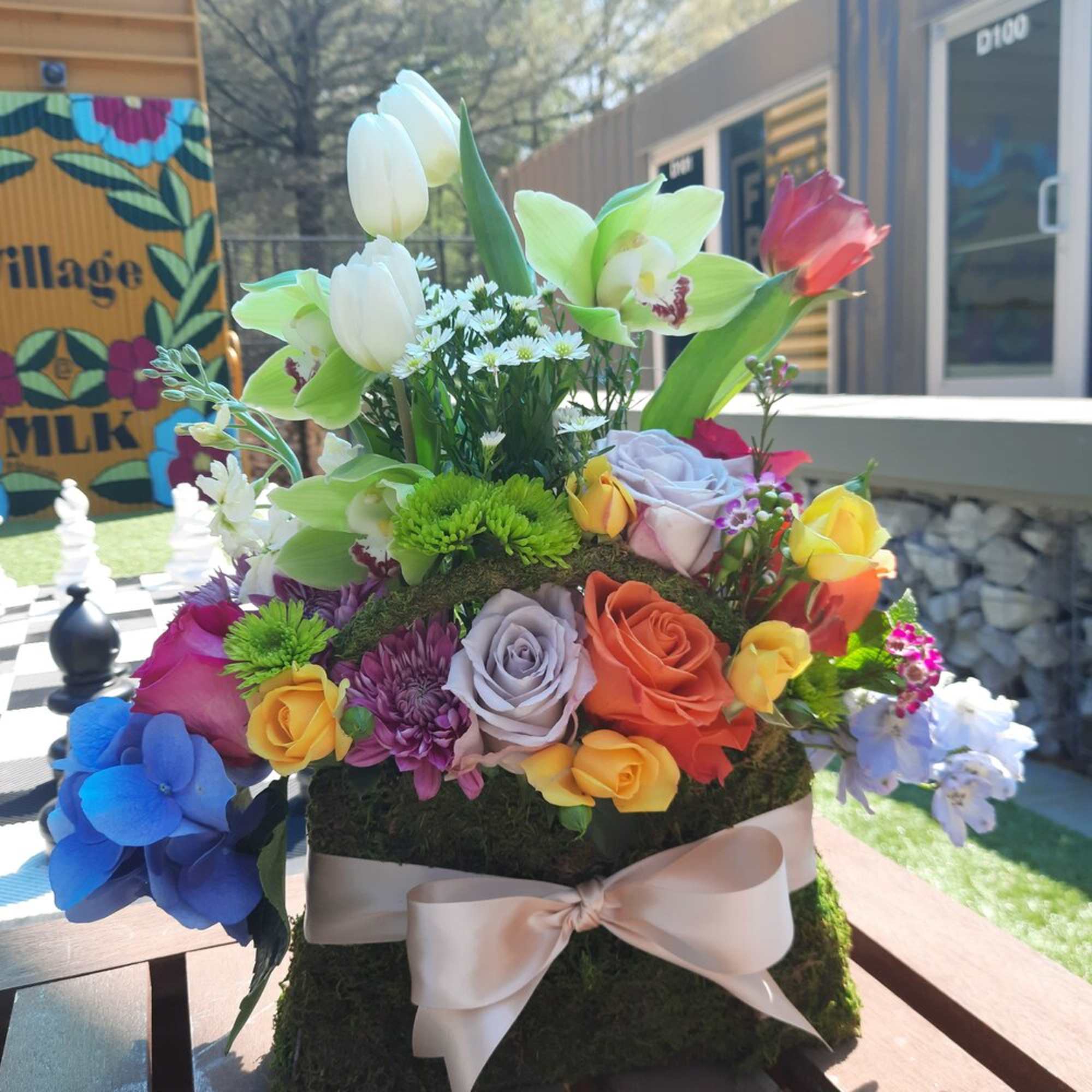 Colorful flower arrangement in a moss-covered box with a ribbon