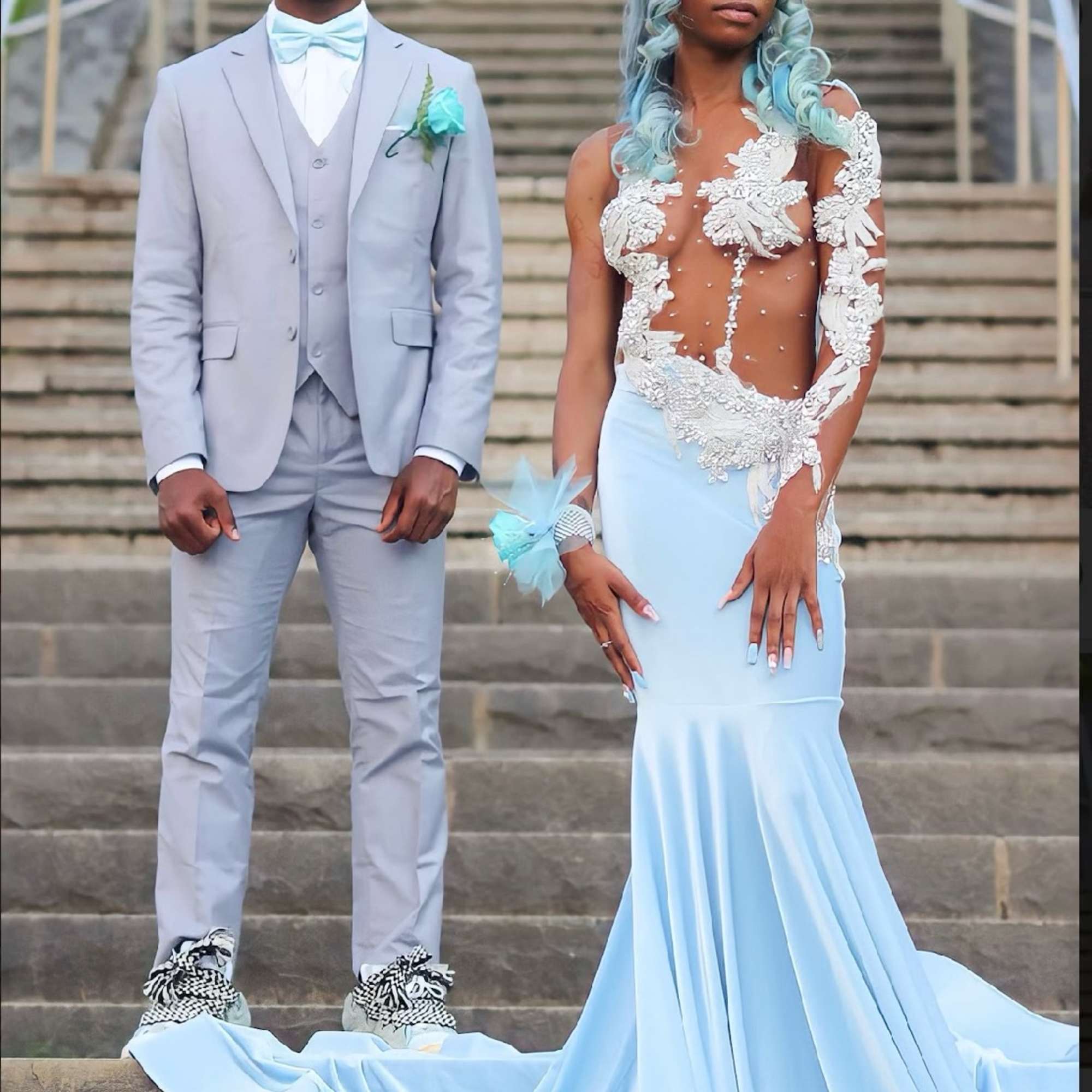 Two people in pale blue formalwear standing on stone steps