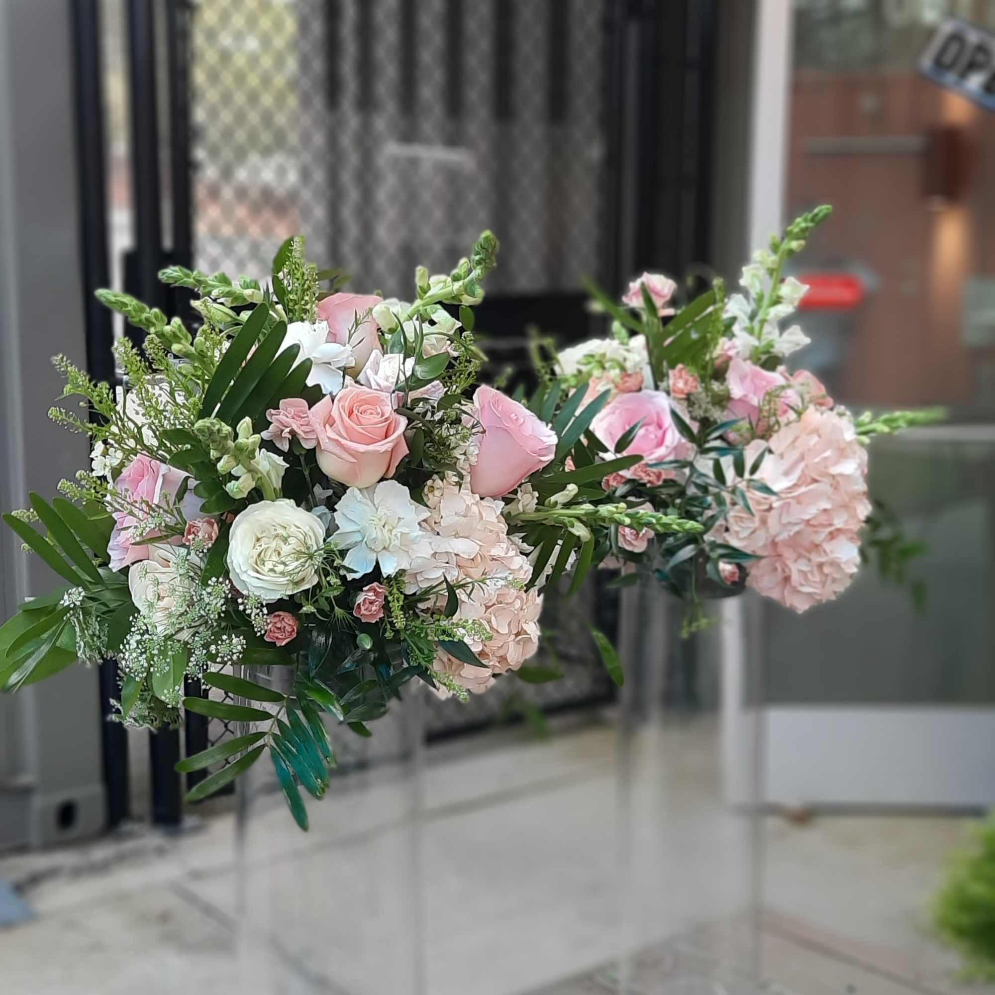 Pink and white floral arrangements in tall clear glass vases