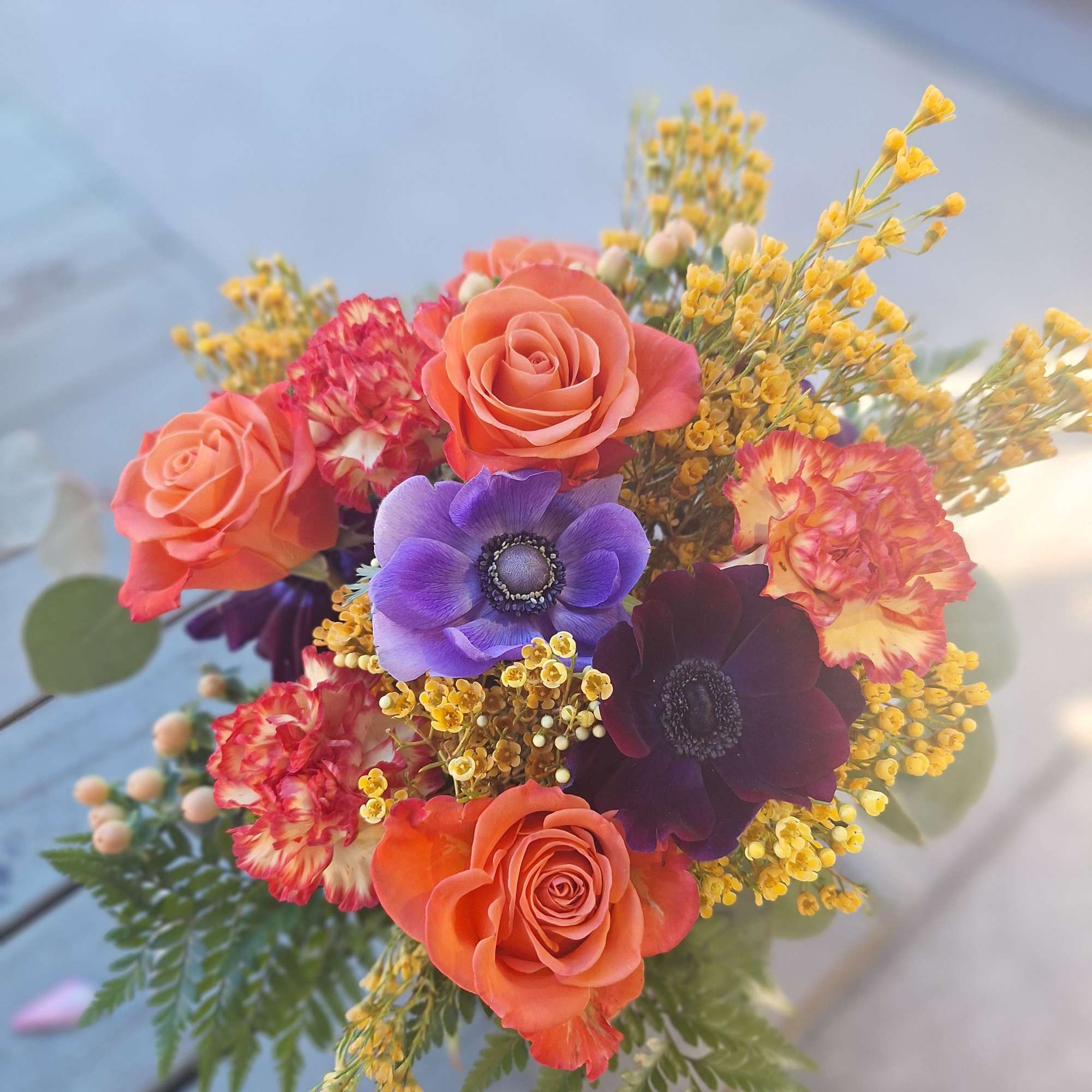 Bouquet of coral roses, purple anemones, and yellow filler flowers
