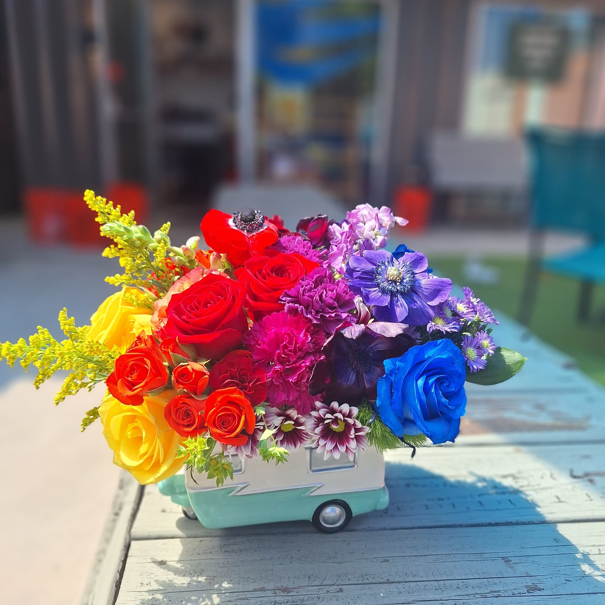 Colorful bouquet of roses and mixed flowers in a small ceramic truck vase