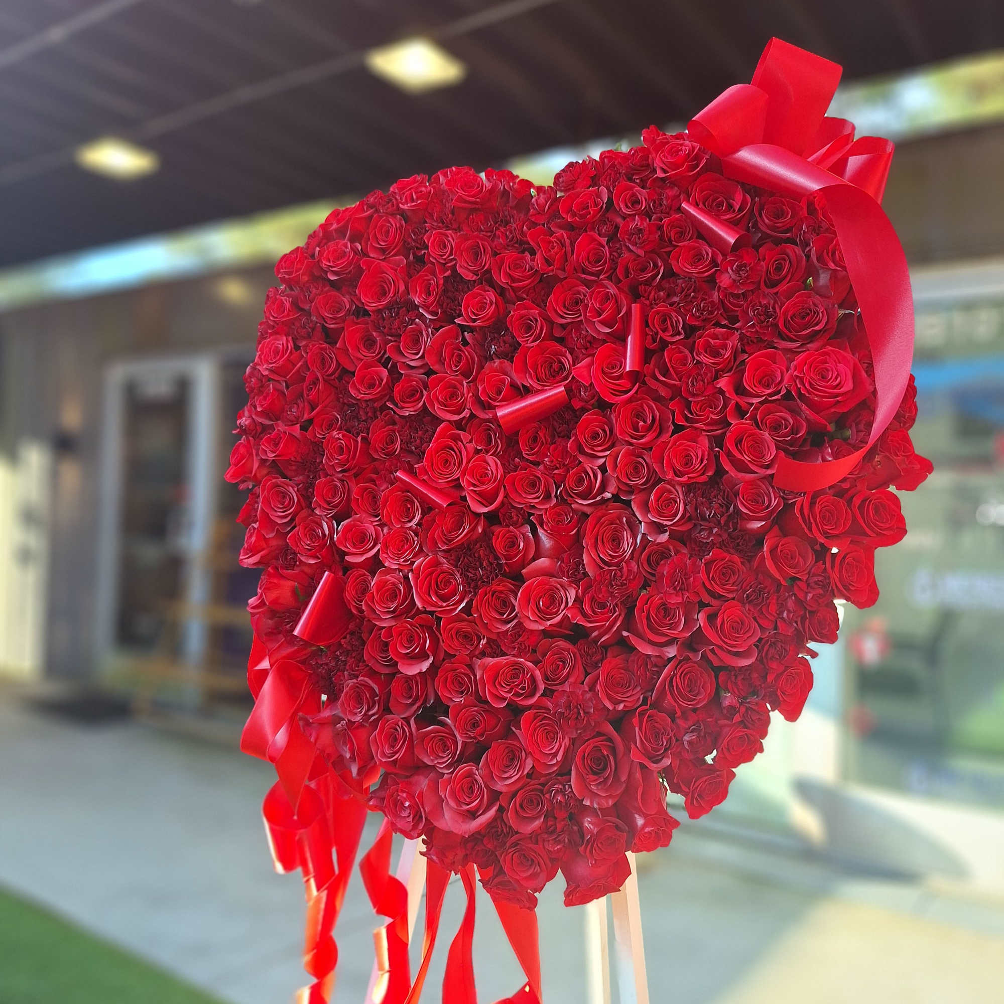 Large heart-shaped arrangement of red roses with red ribbon streamers