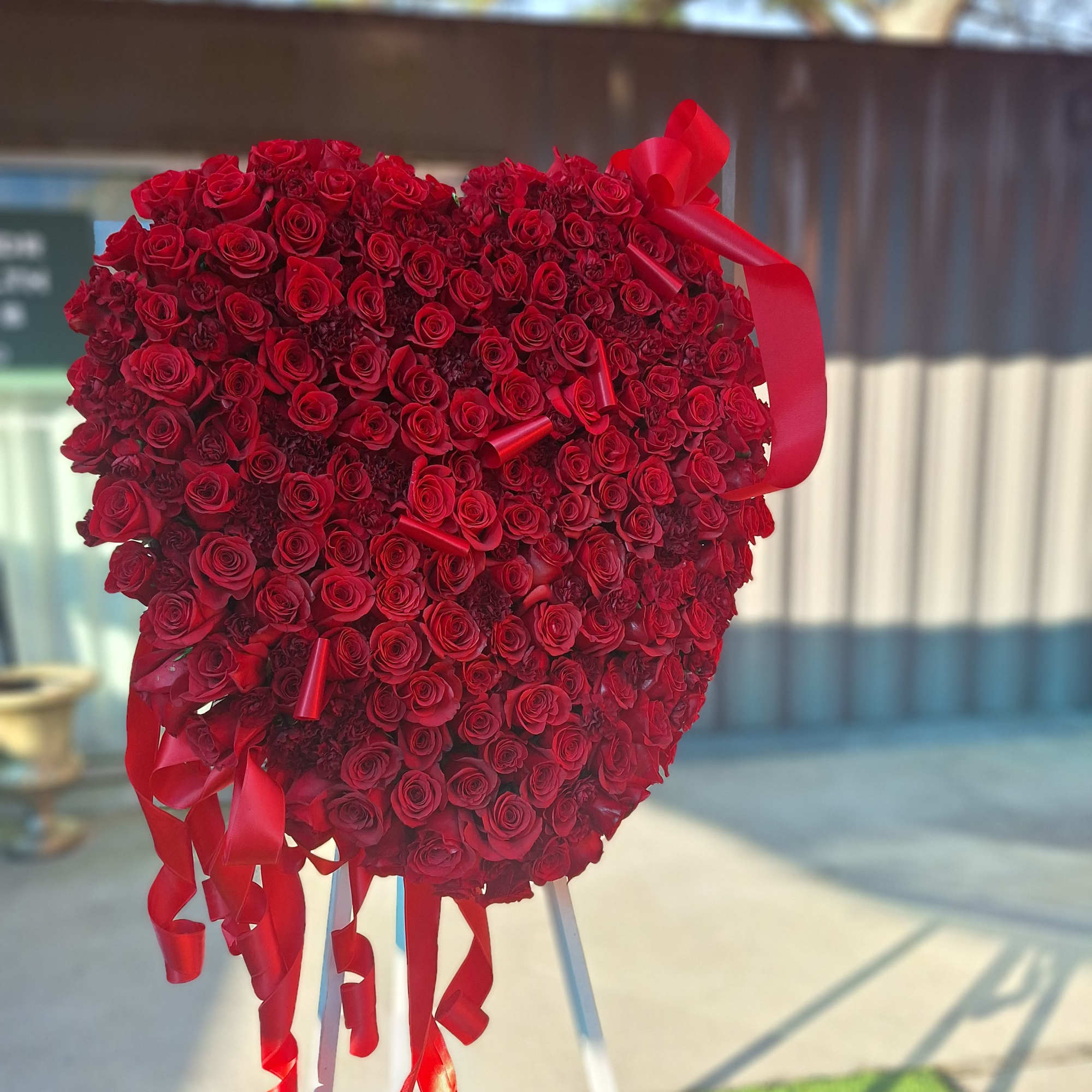 Heart-shaped arrangement of red roses with ribbon streamers