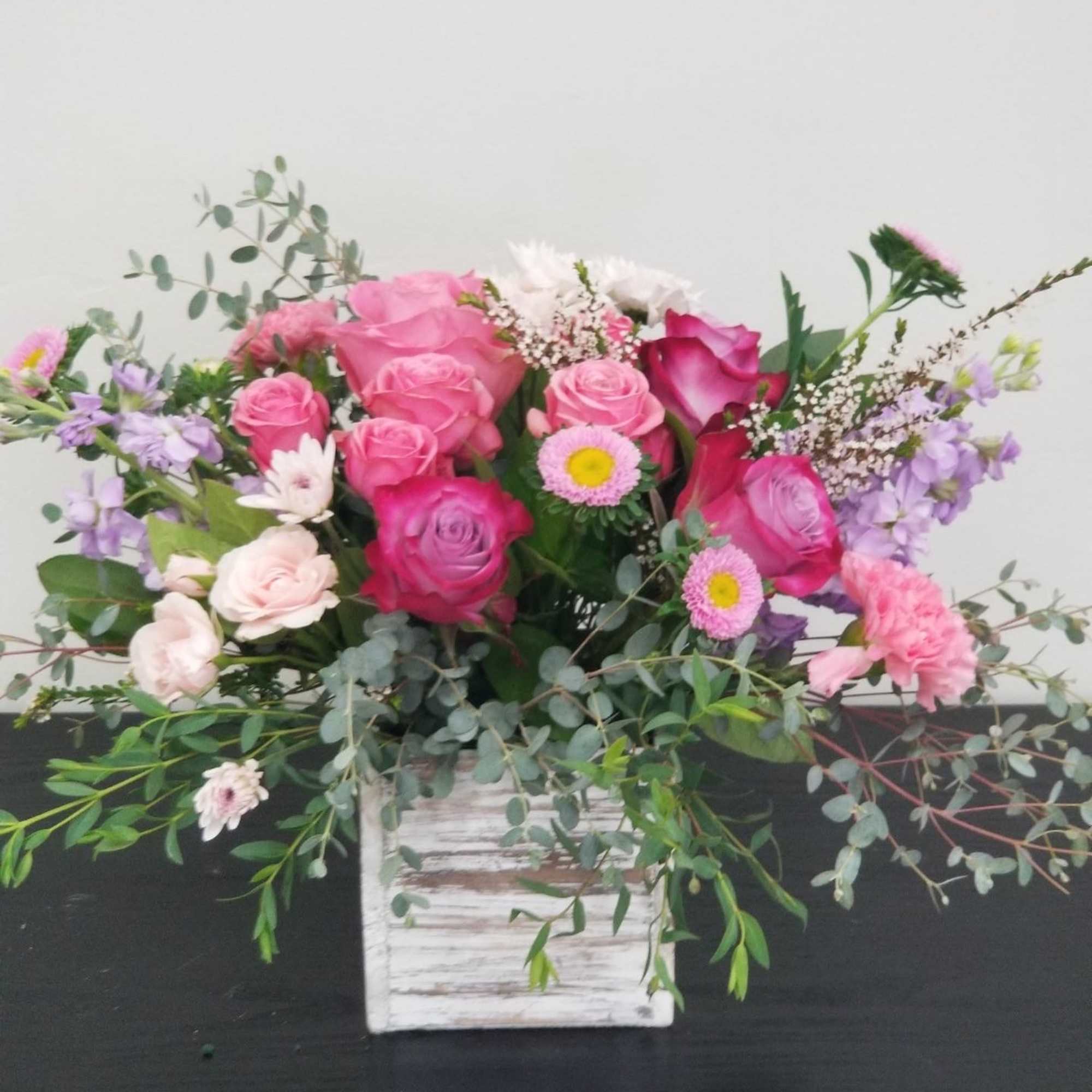 Pink and lavender rose bouquet in a white wooden box