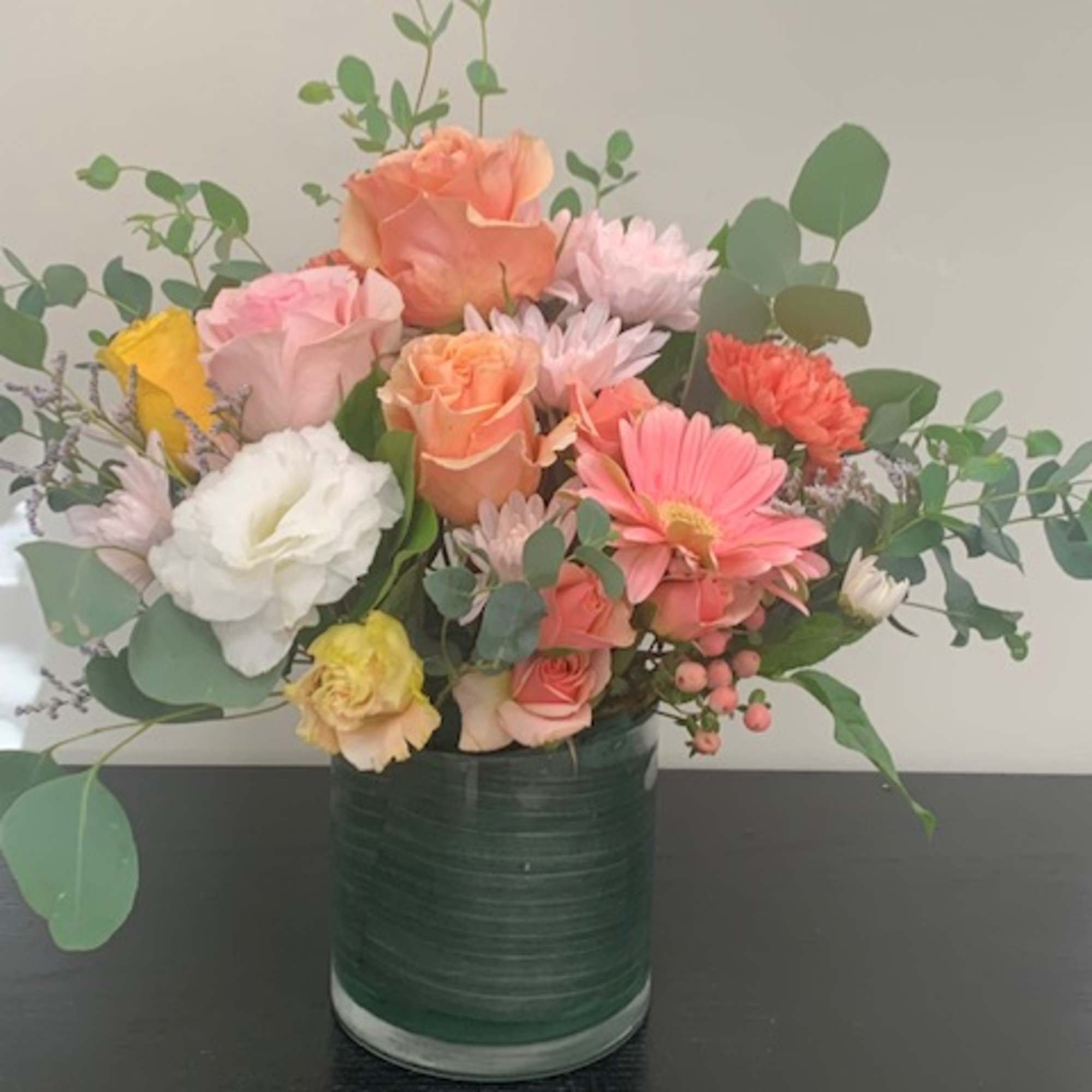 Mixed bouquet of pastel flowers in a green glass vase