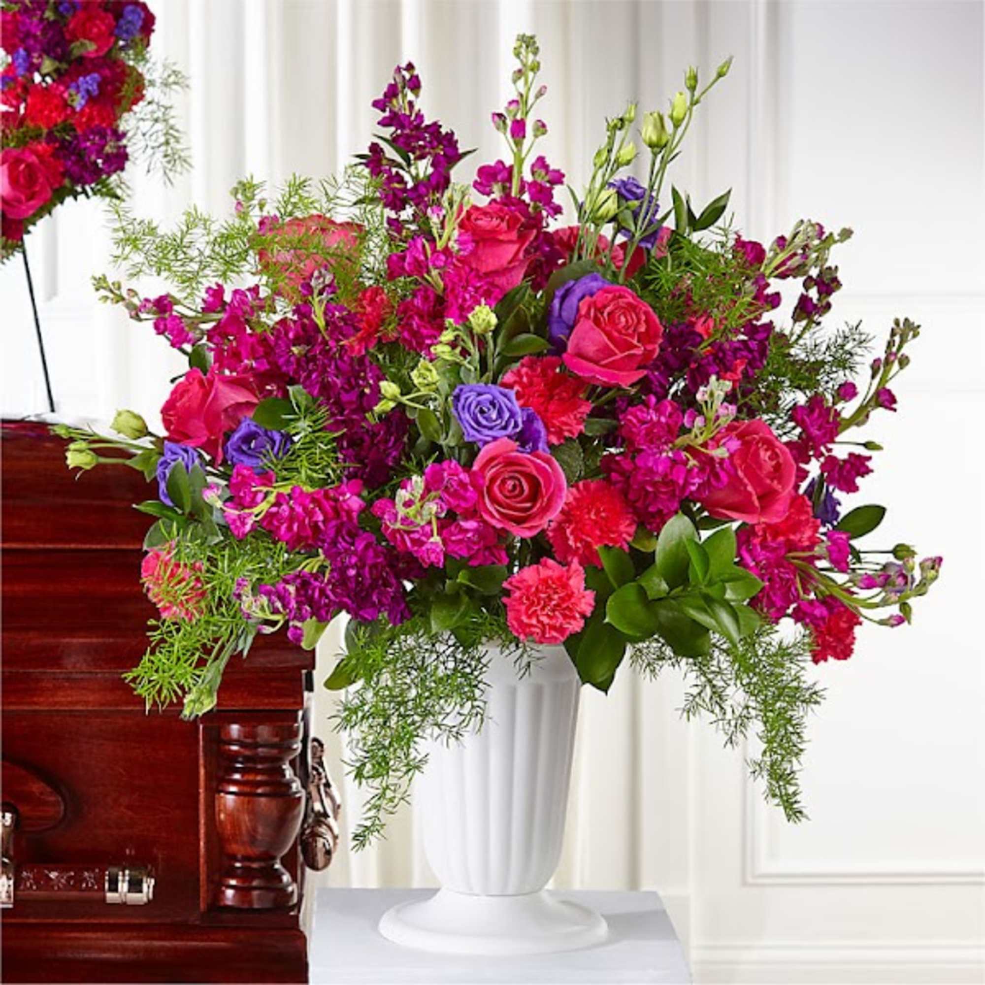Bright pink and purple floral arrangement in a white vase