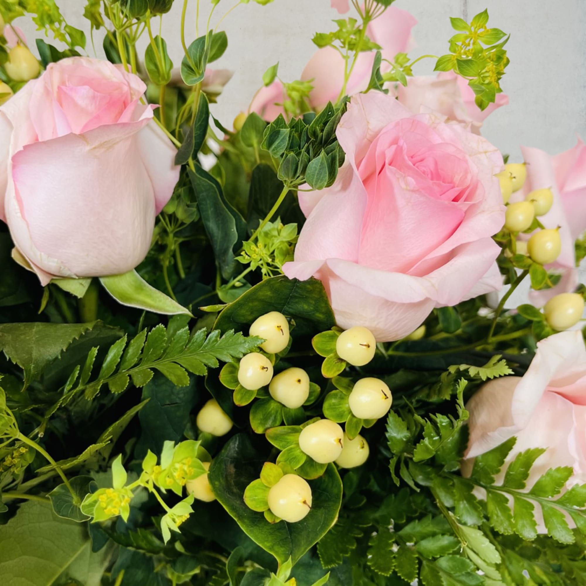 Pink roses with green foliage and pale berry accents