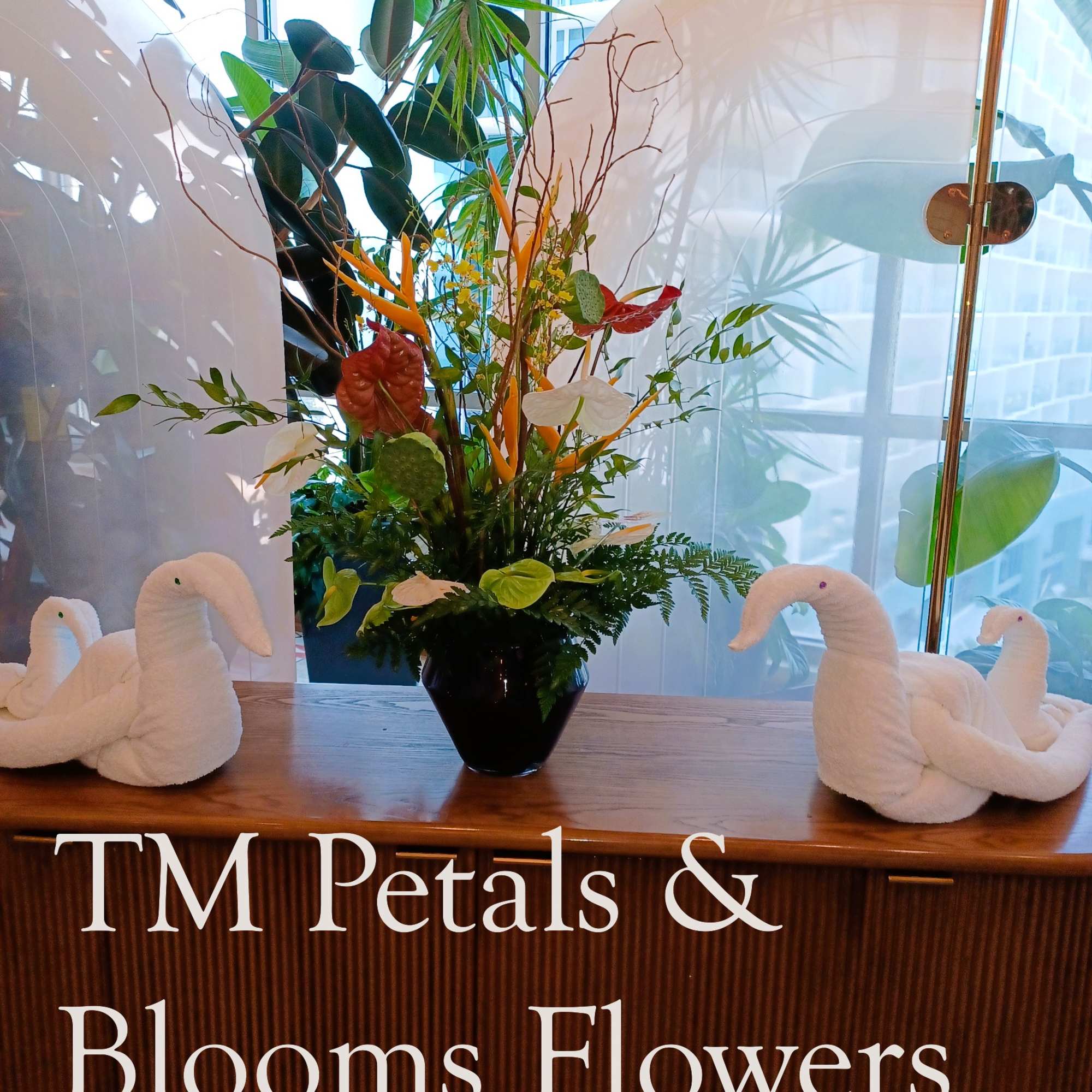 Tropical flower arrangement in a black vase with white swan decorations