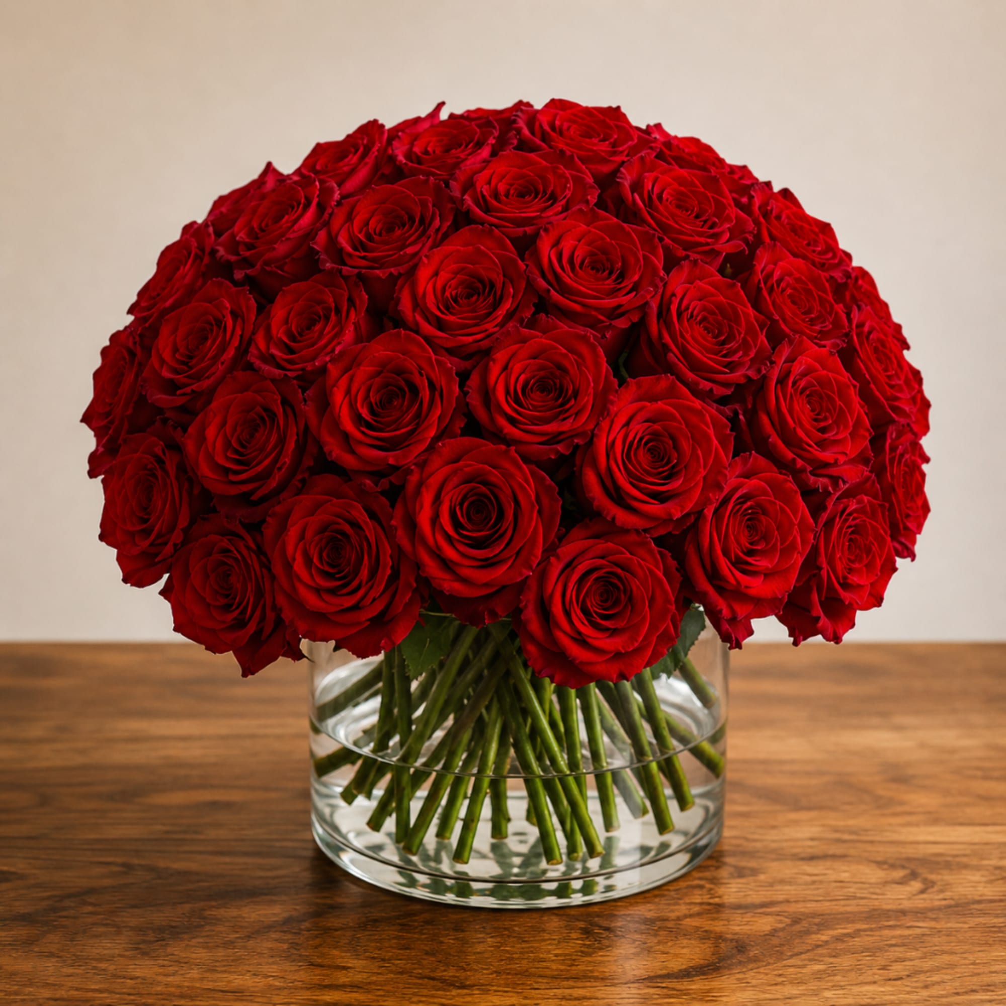 Red roses arranged in a clear glass vase on a wooden table