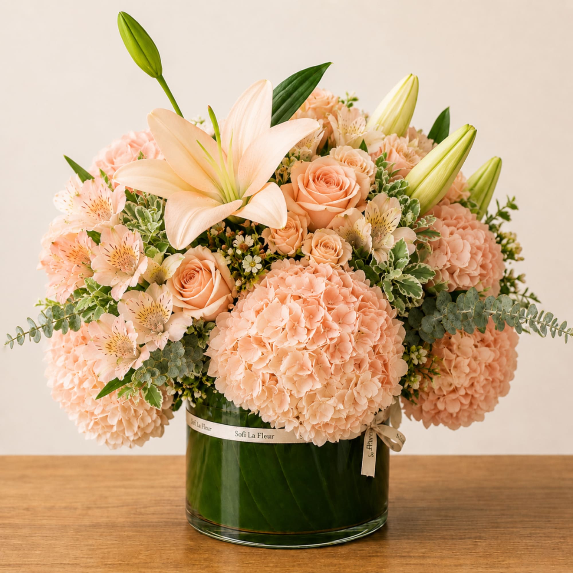 Peach bouquet with lilies, roses, and hydrangeas in a glass vase