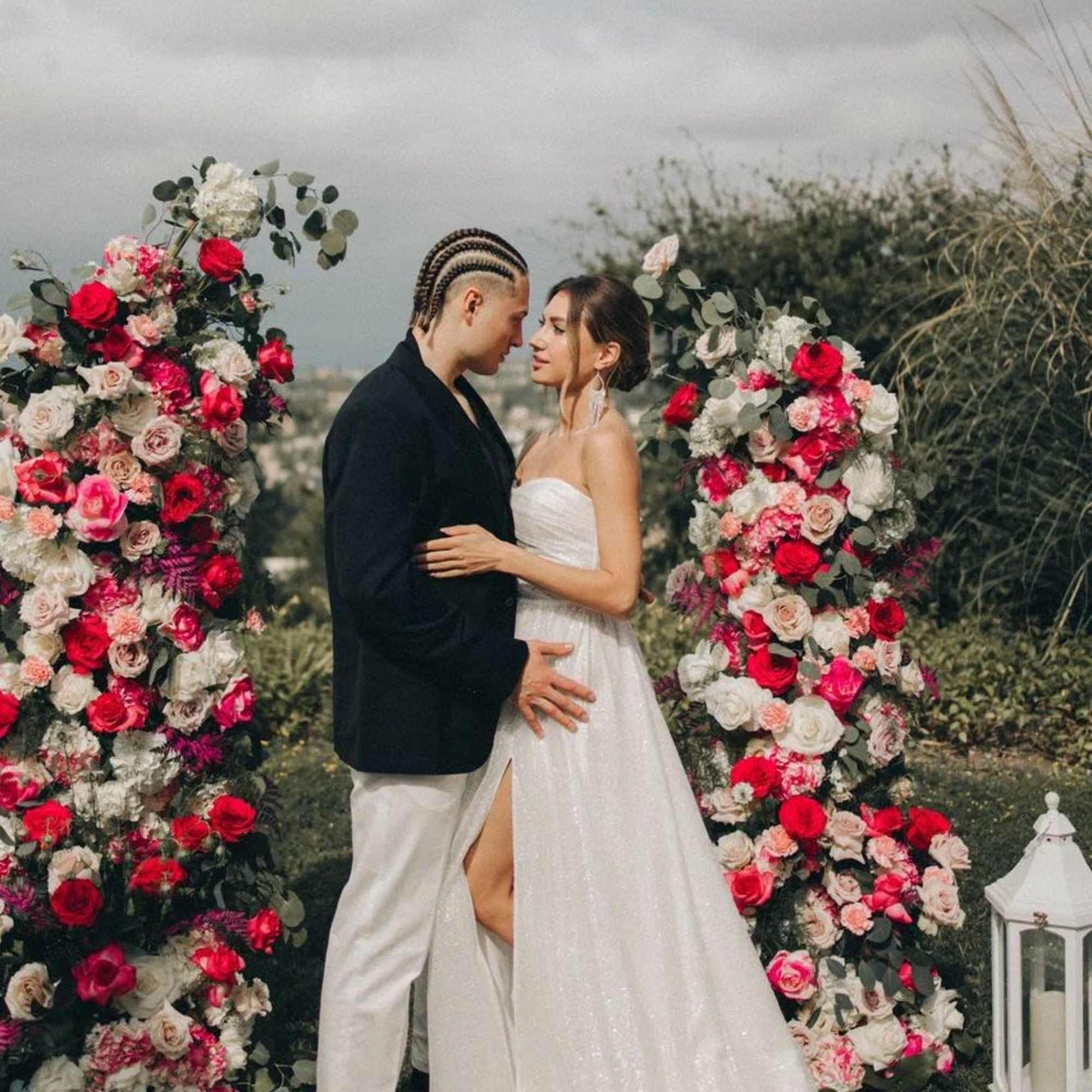 Tall red, pink, and white rose ceremony pillars framing a couple outdoors