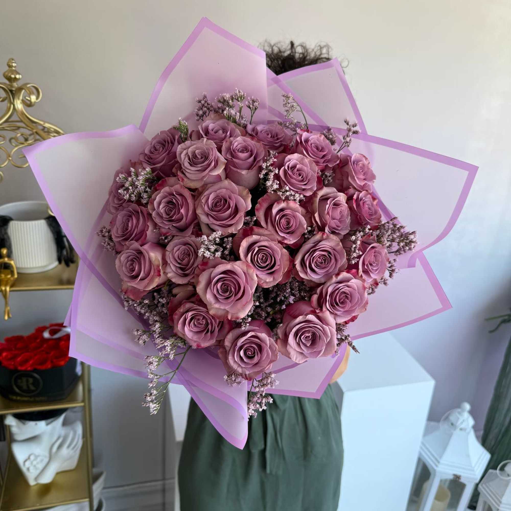 Large hand-tied bouquet of lavender roses with delicate filler flowers wrapped in translucent pink paper
