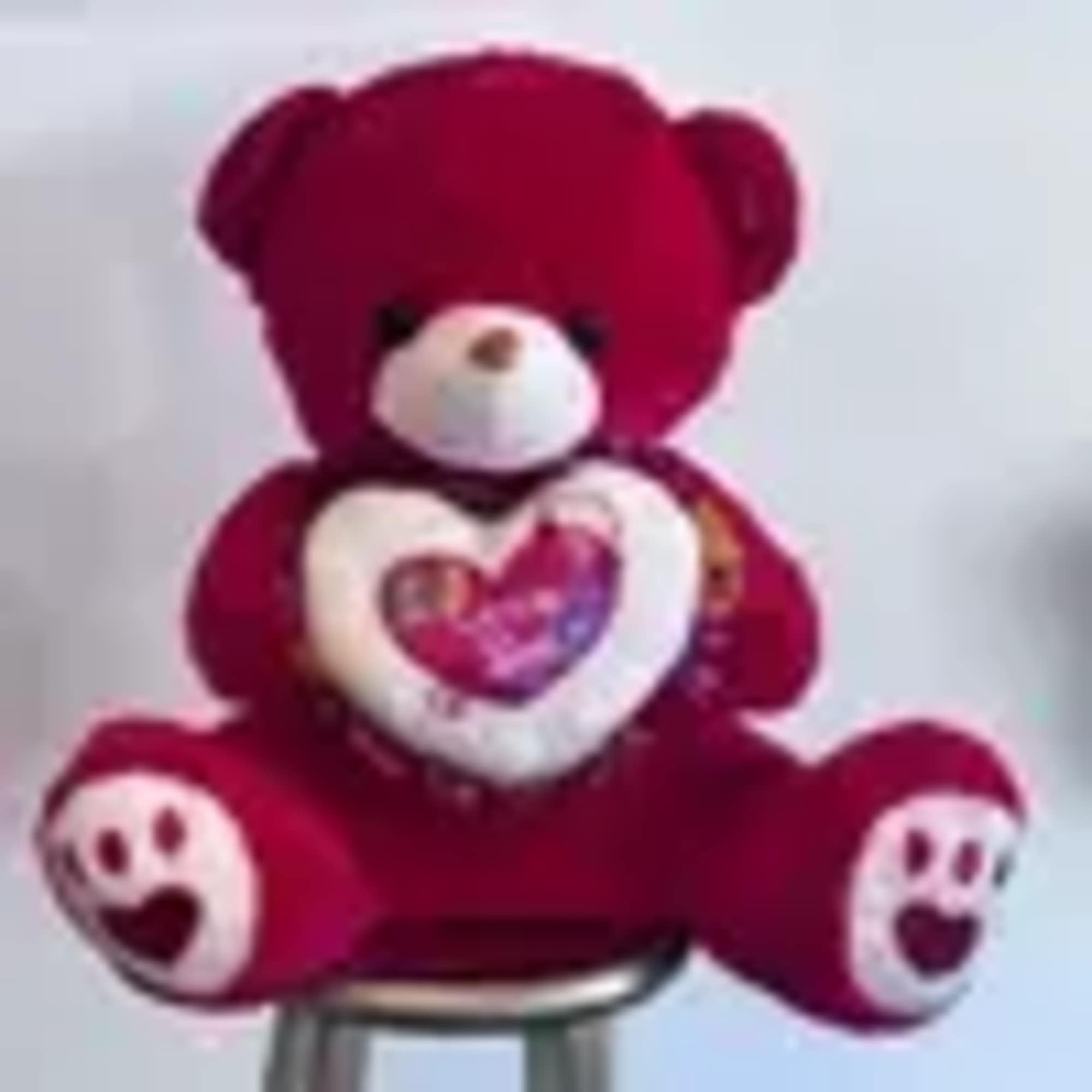Red teddy bear holding a heart-shaped pillow