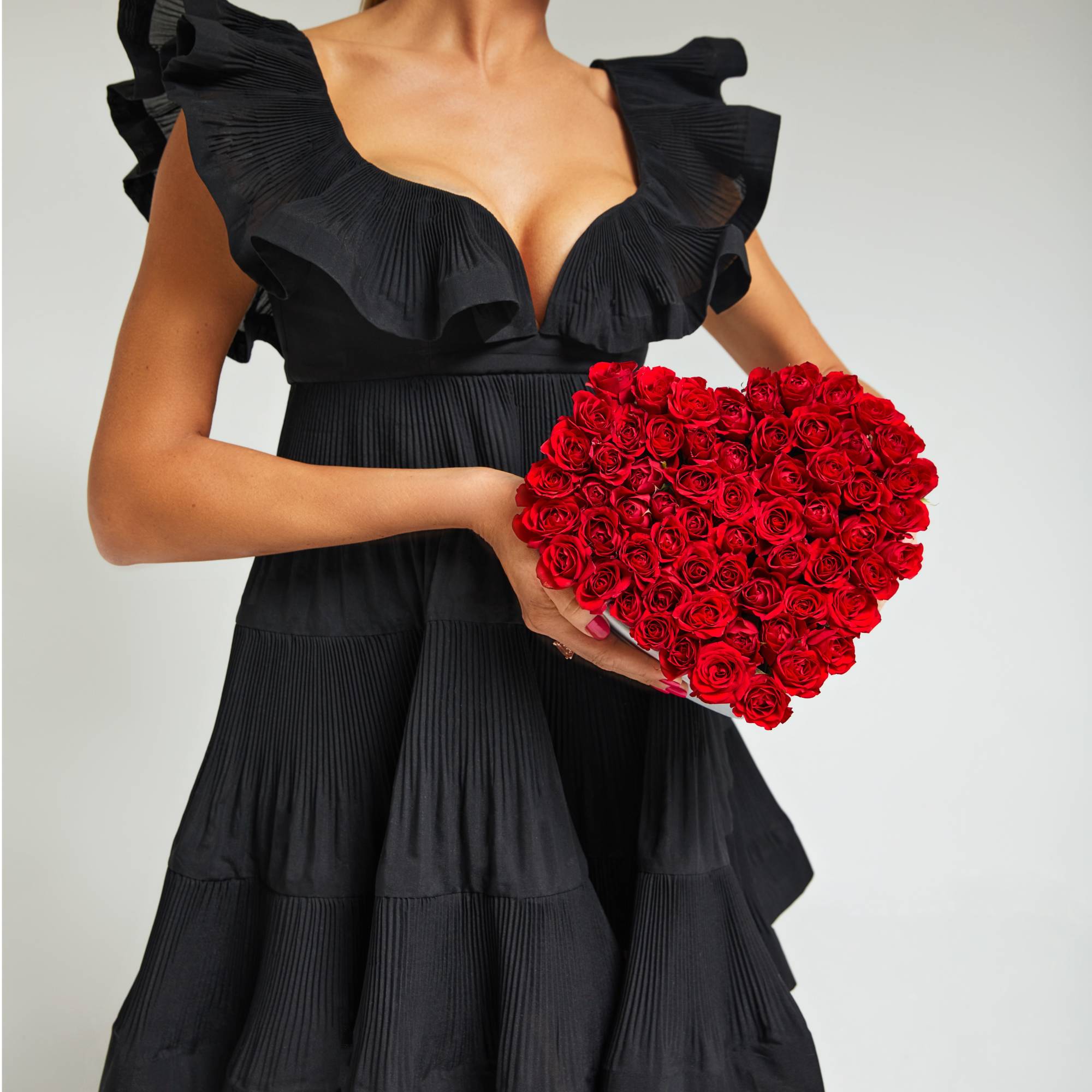 Woman holding a heart-shaped bouquet of red roses
